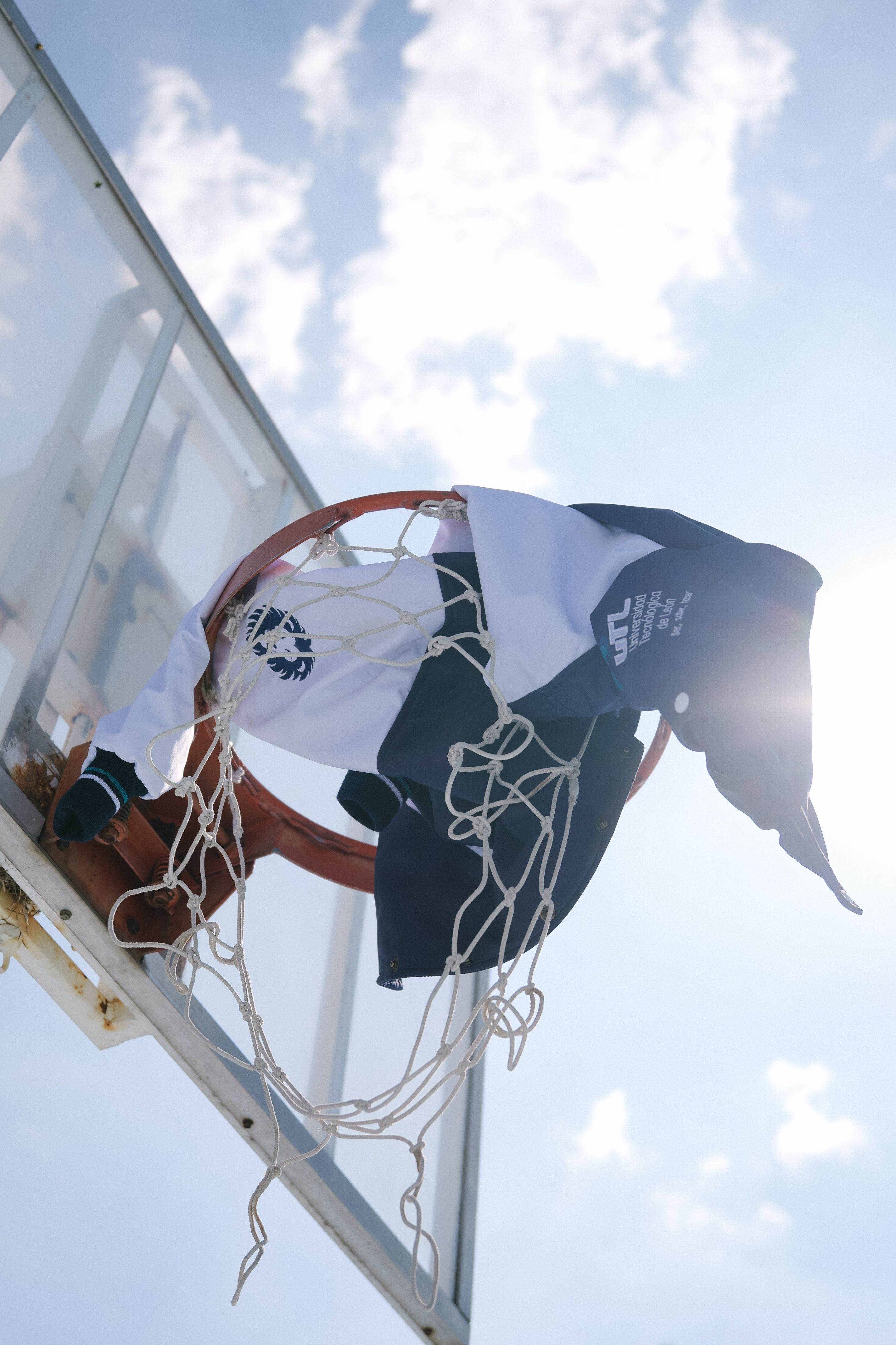 Sweatshirt caught on a basketball hoop, captured on a sunny day outdoors.