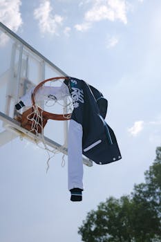 A sports jacket draped over a basketball hoop under a clear sky in León, Mexico.