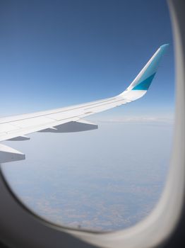 Scenic view of airplane wing during flight, captured from passenger window against clear blue sky.