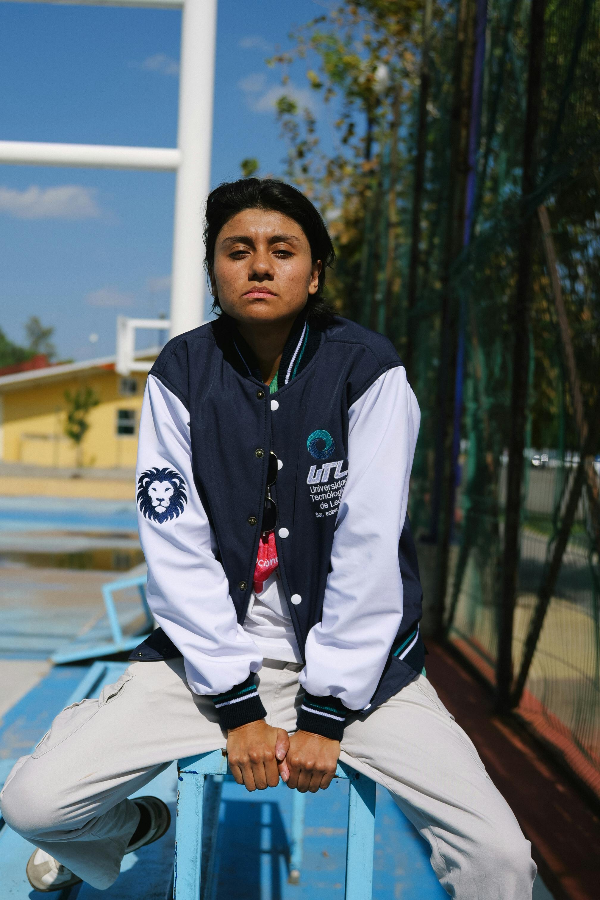 Gratis Una giovane donna sicura di sé è seduta sugli spalti di un'area sportiva all'aperto a León, in Messico. Foto a disposizione