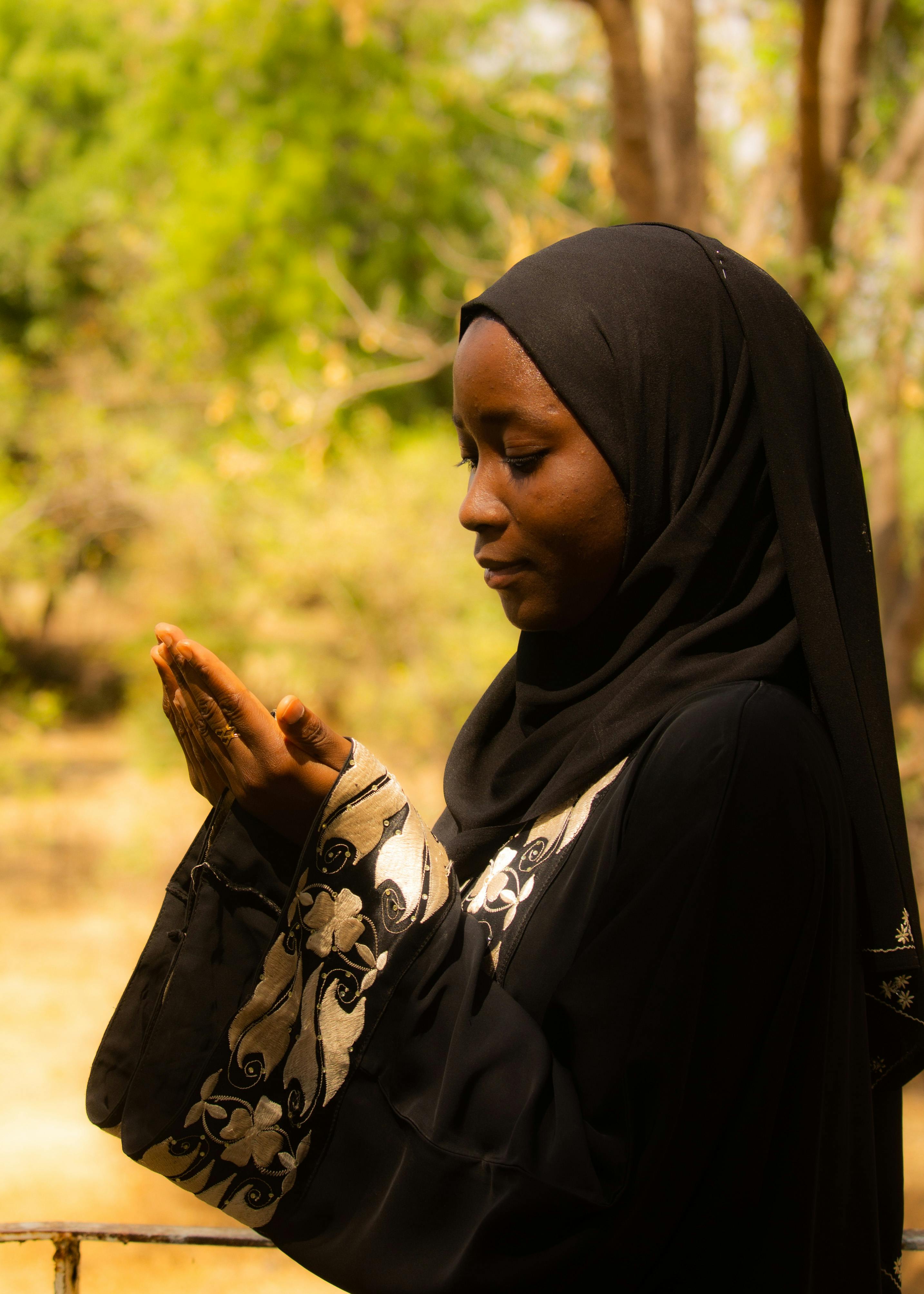 Serene portrait of a woman in traditional attire praying in a lush forest setting.
