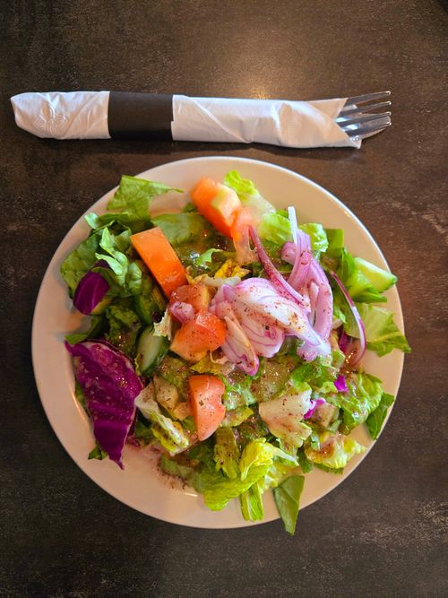 Free Top view of a colorful garden salad on a wooden table with a fork and napkin. Stock Photo