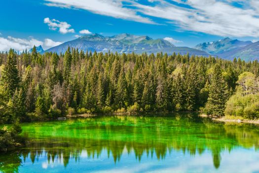 Beautiful emerald lake surrounded by lush forest in Jasper National Park, Alberta.