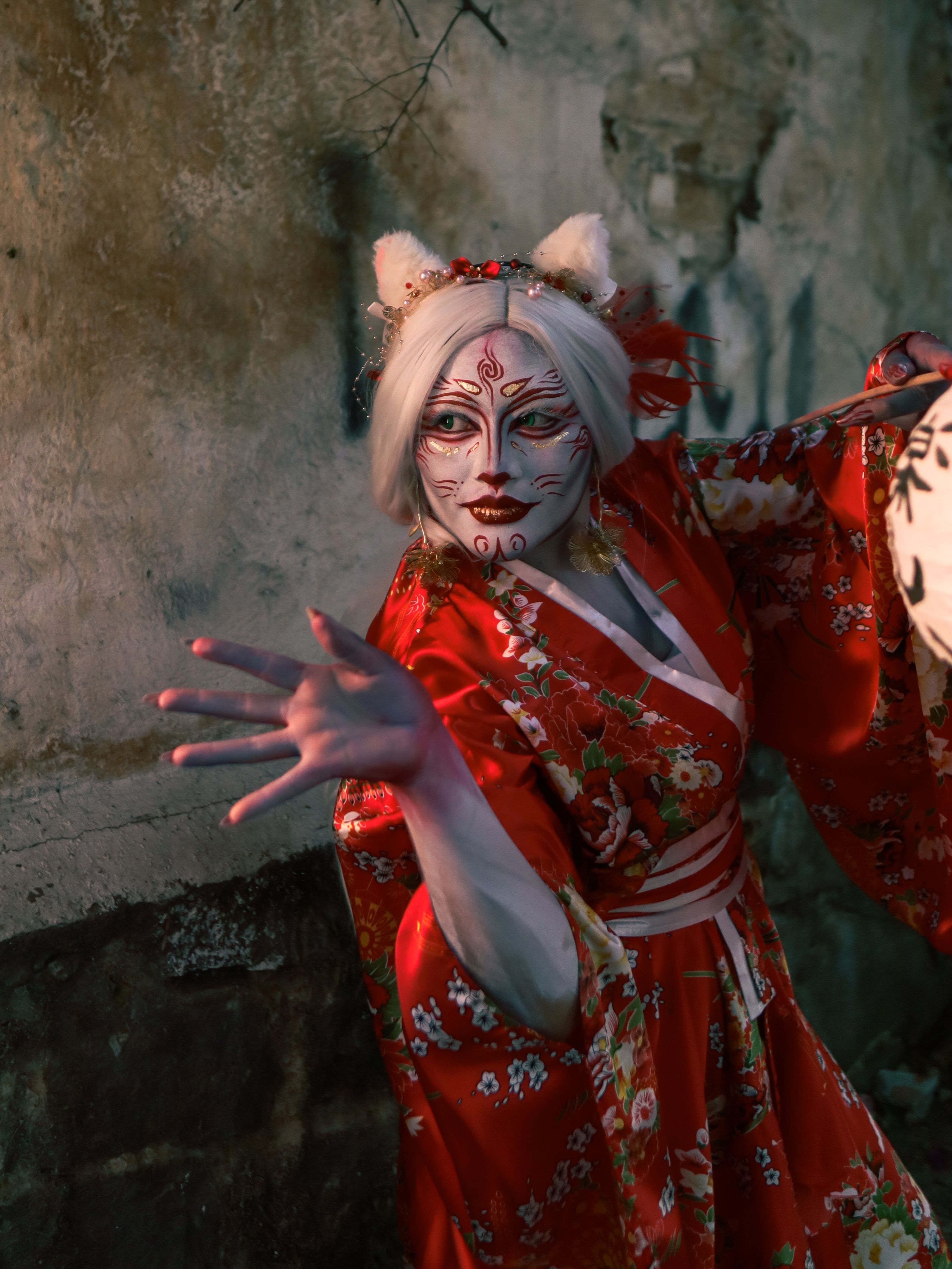 Striking image of a woman in a red kimono with fantasy makeup and fox ears in a mystical setting.