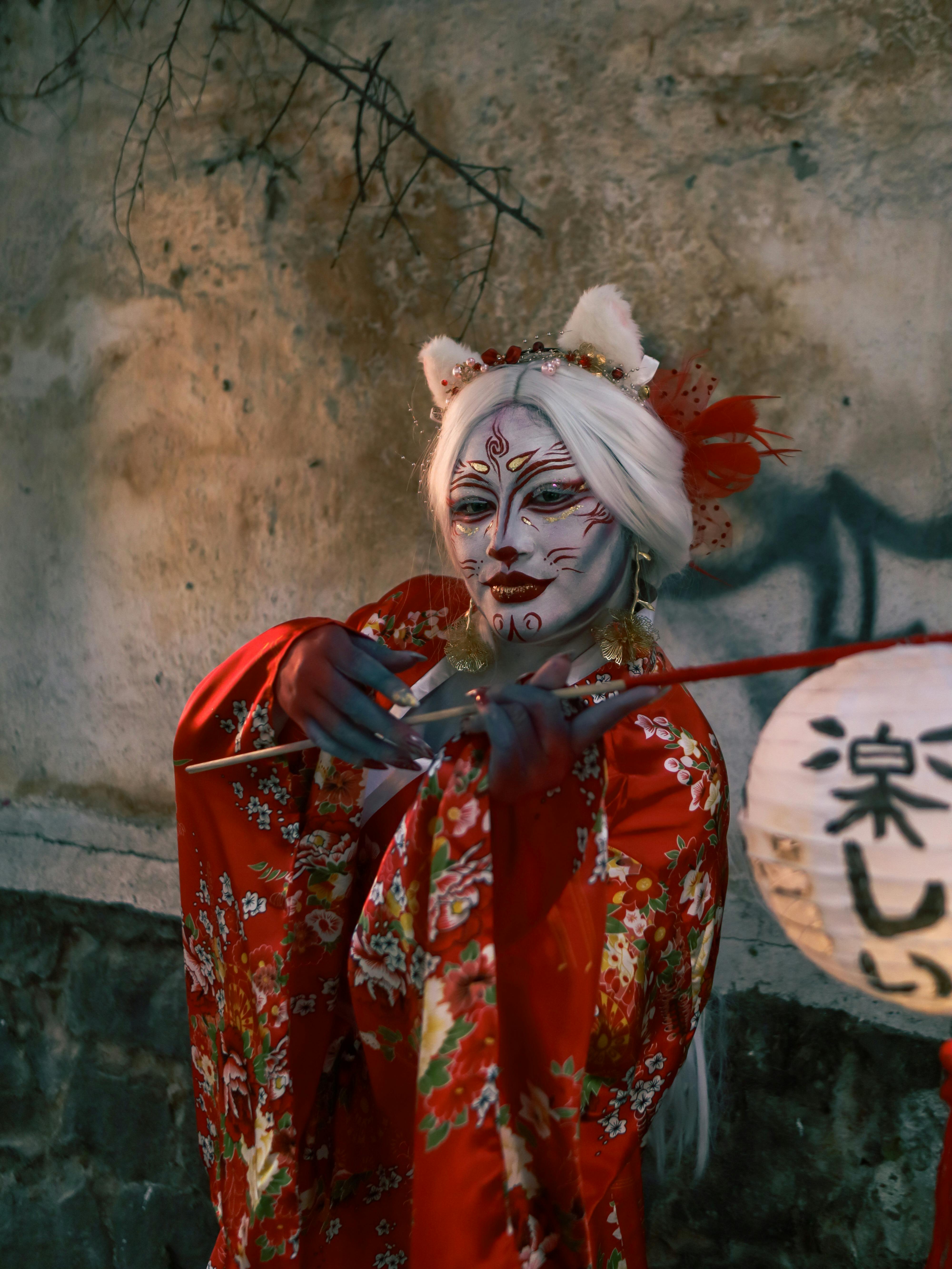 Ücretsiz Kırmızı kimono ve şeytan maskesi giymiş büyüleyici bir performans sanatçısı, sanatsal bir sahnede görüntülendi. Stok Fotoğraflar