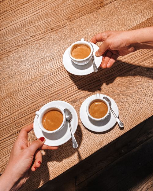 Free Three people sharing espresso at a wooden table in London, England. Stock Photo