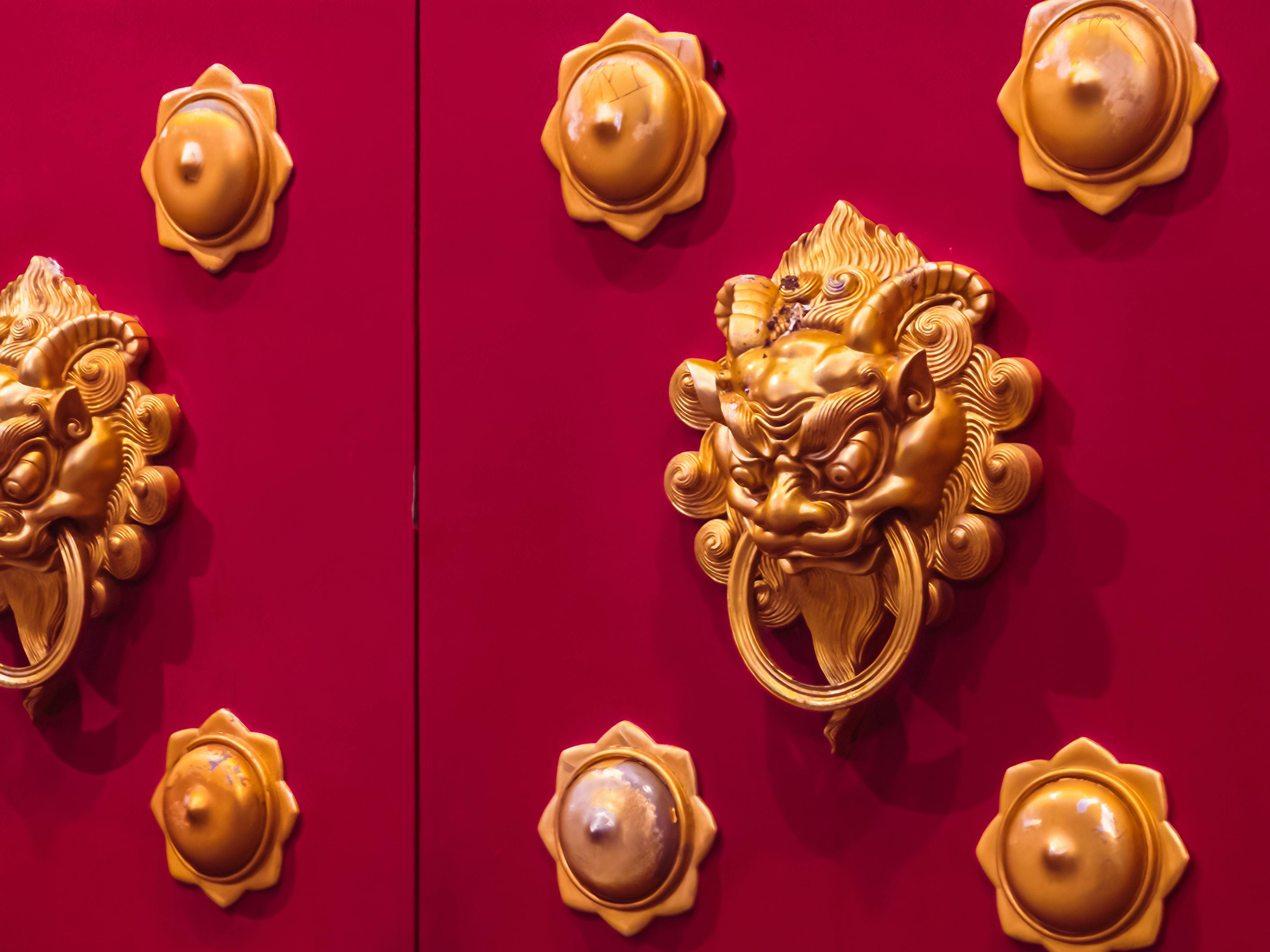 Kostnadsfria Närbild av en utsmyckad dörrknackare med gyllene lejonhuvud på en traditionell röd tempeldörr i Xia Men Shi, Kina. Stock foto