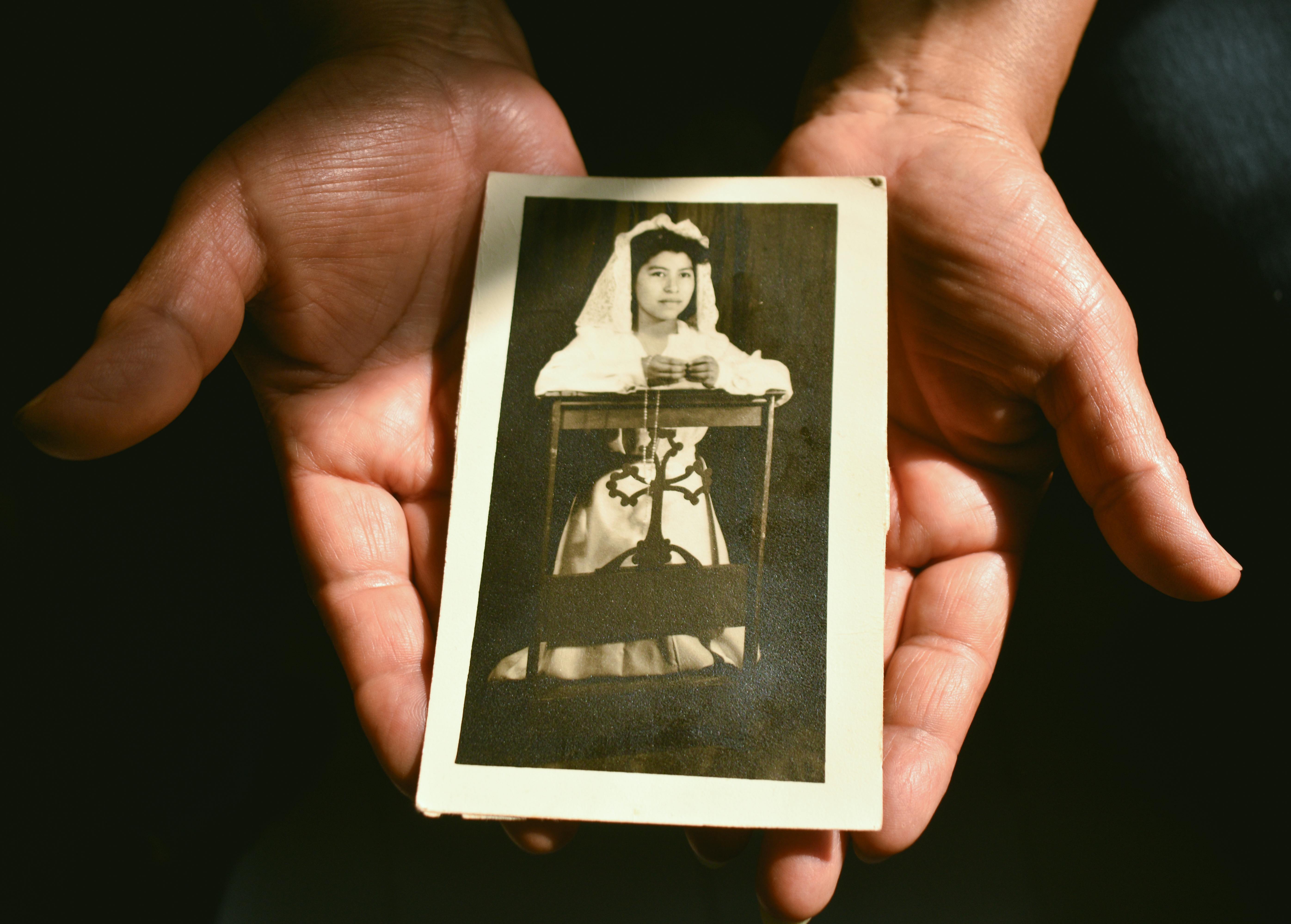 Bezpłatne Dłonie trzymające starą fotografię młodej dziewczyny w stroju komunijnym, symbolizującą nostalgię. Zdjęcie z galerii