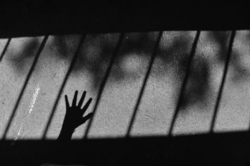 Free Artistic black and white photo of a hand shadow cast on a concrete surface with striped shadows. Stock Photo