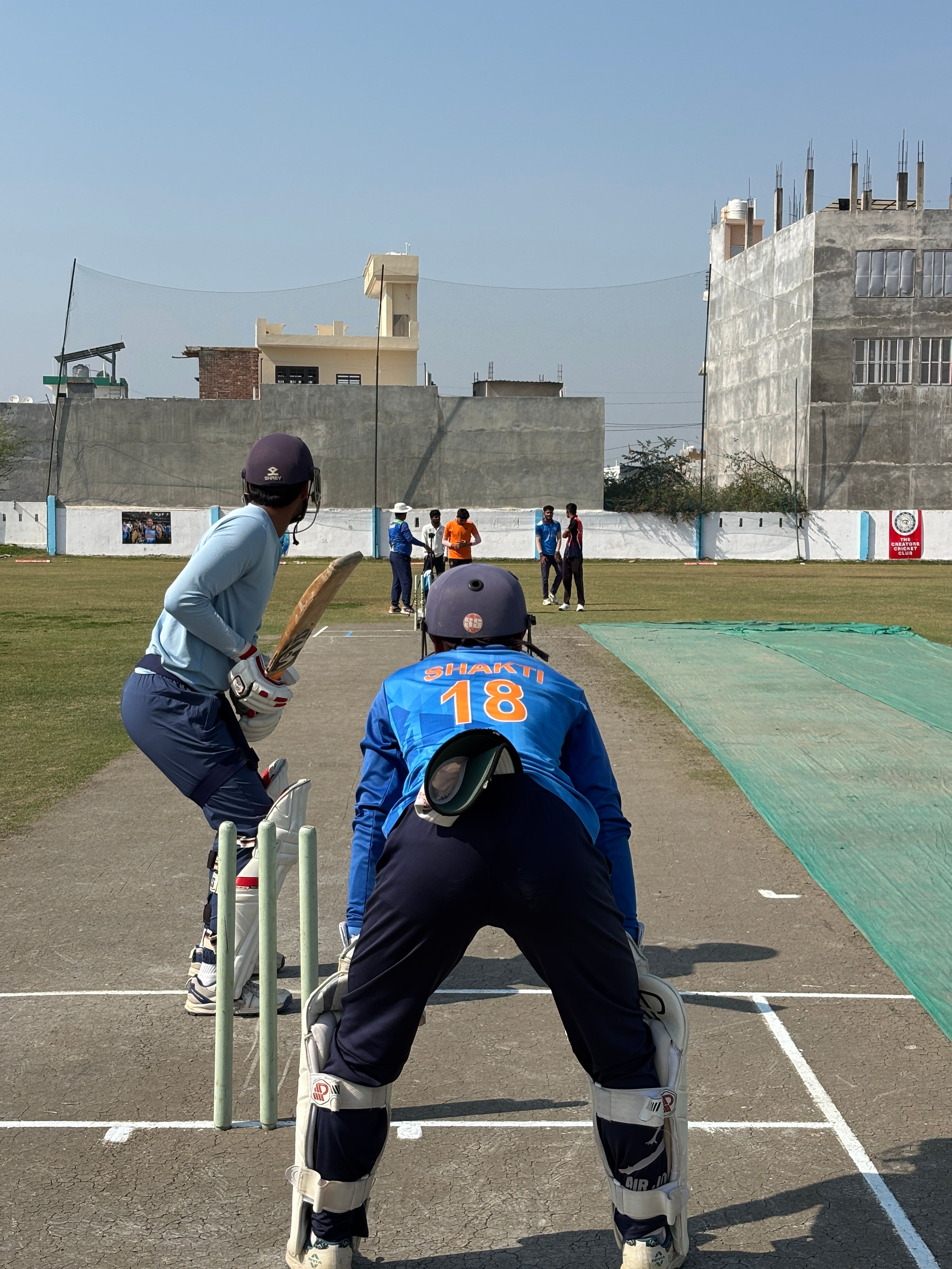 Young athletes playing cricket at a local field in Lucknow on a sunny day, showcasing teamwork and sportsmanship.