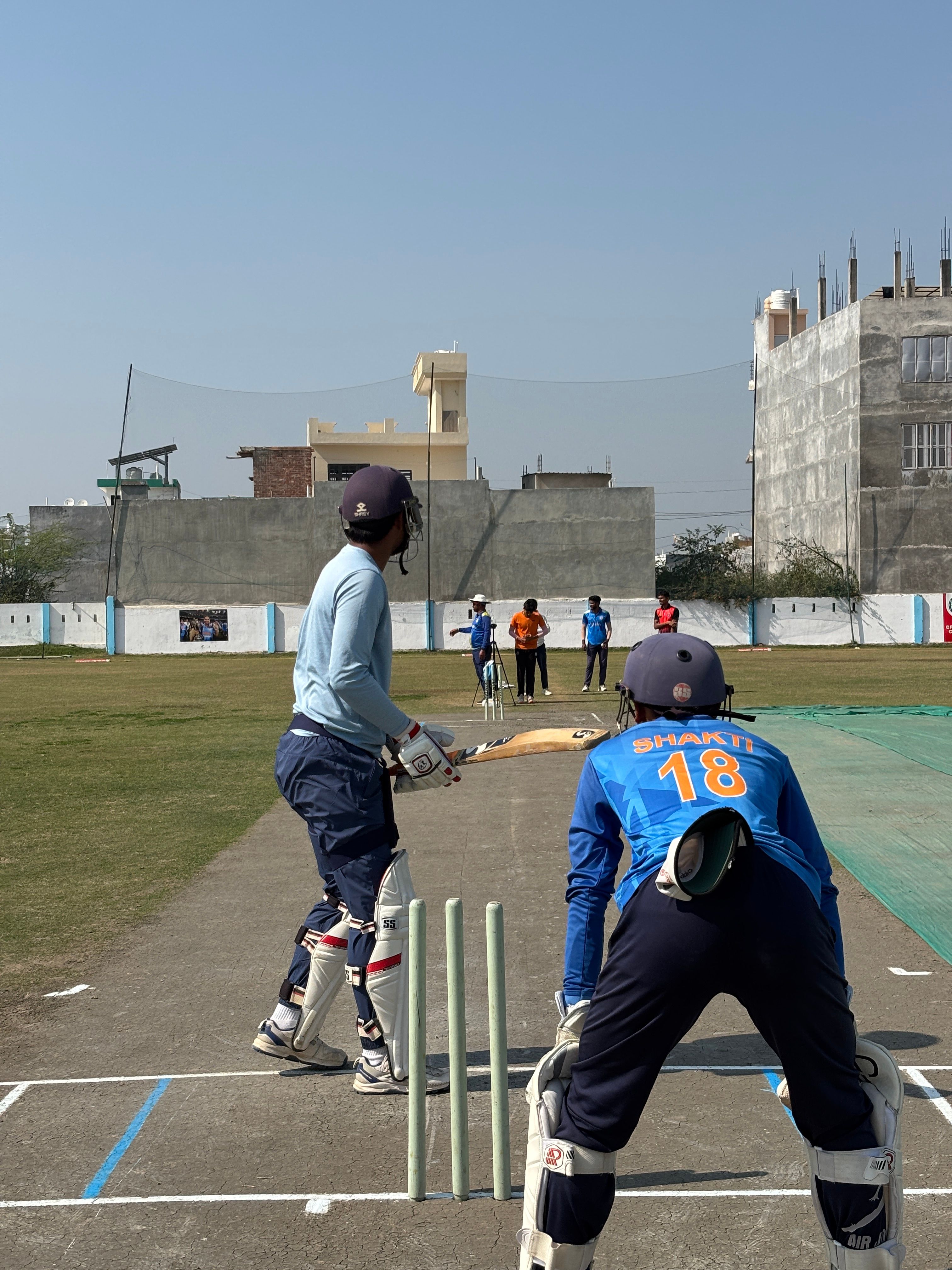 Action-packed cricket game on a sunny day, capturing young players in an urban setting, highlighting teamwork and sportsmanship.