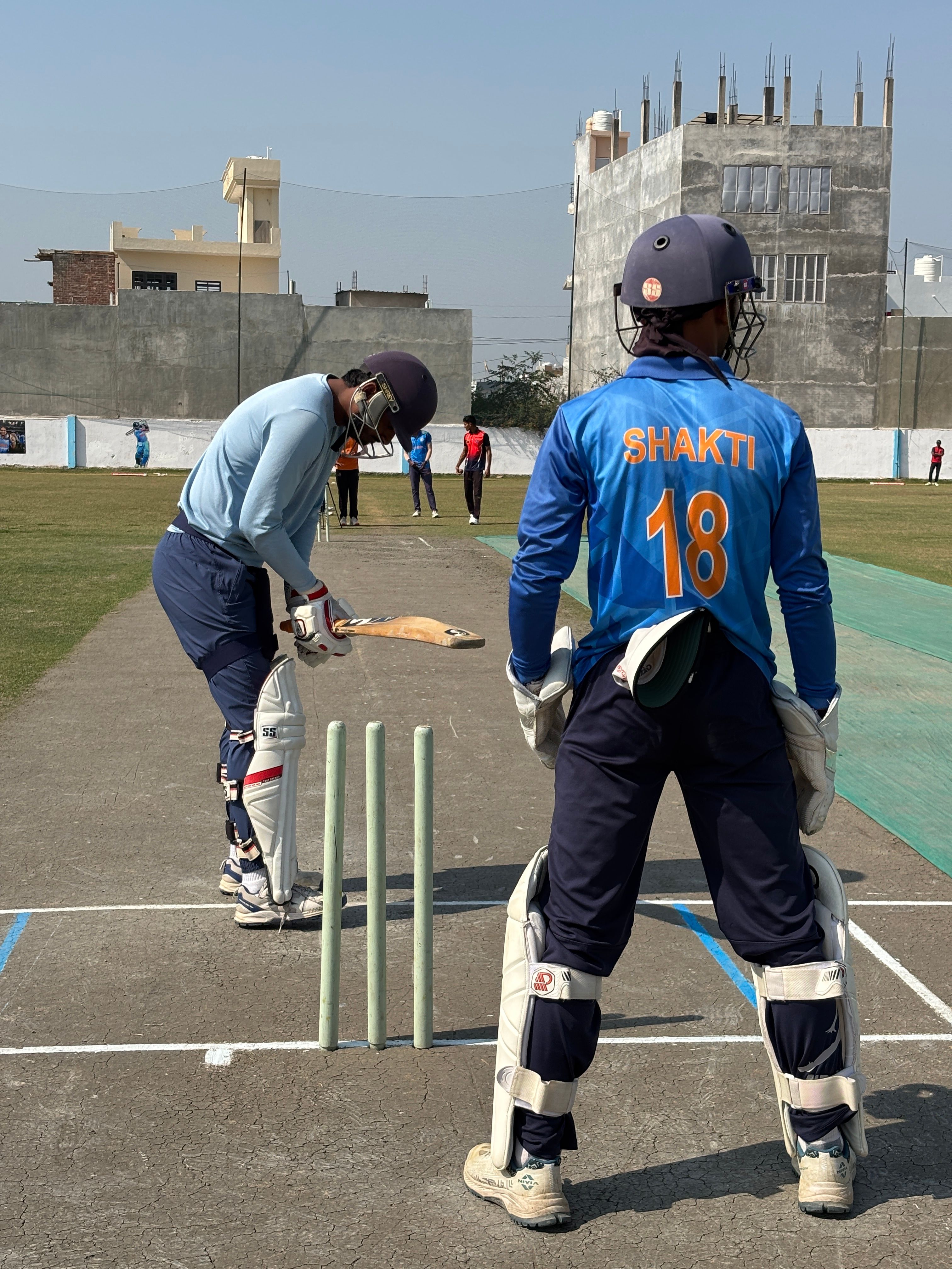Cricketers during practice session on a sunny day, focusing on batting skills.