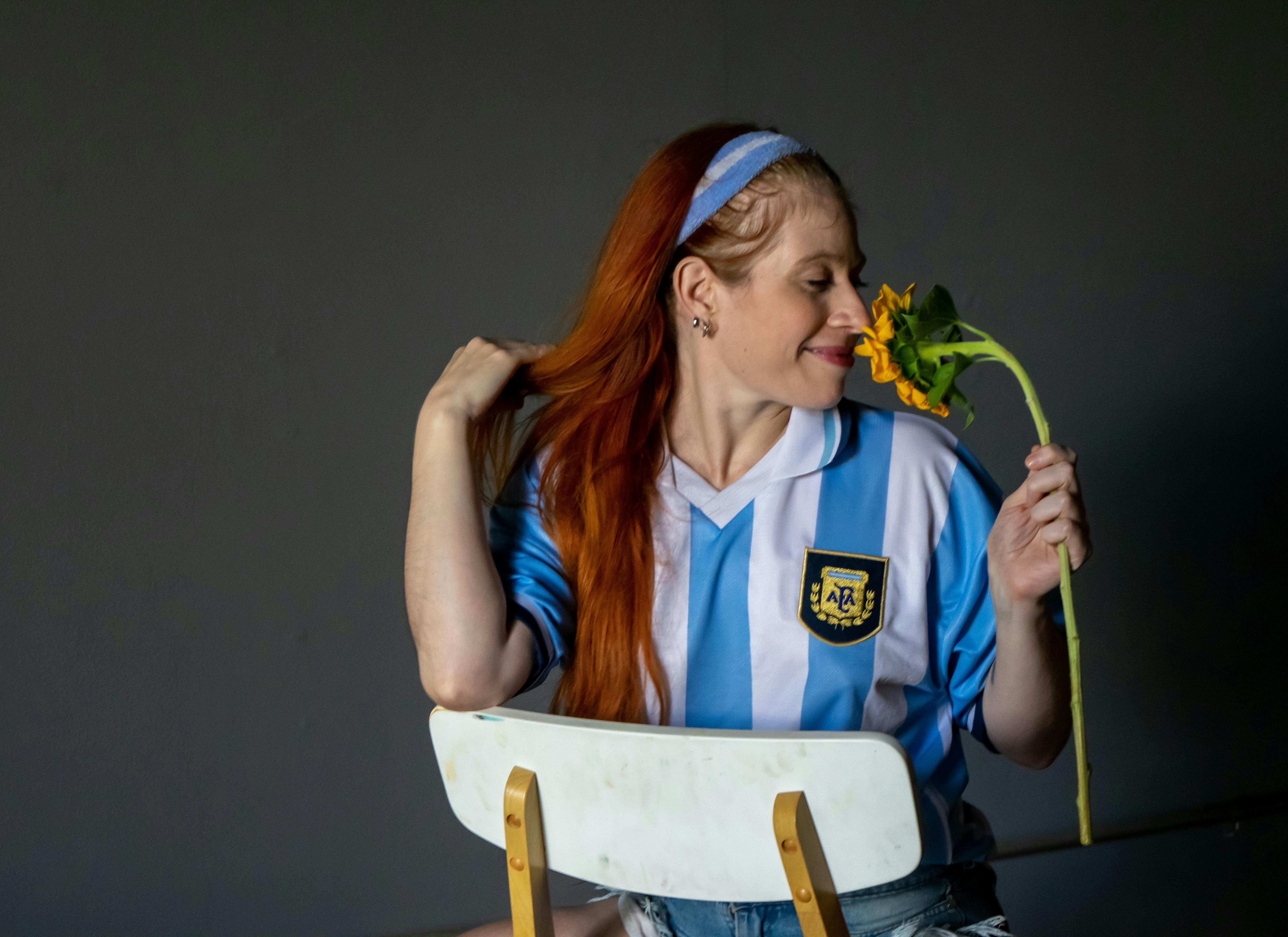 Ücretsiz İç mekanda mavi spor forması giyen ve elinde ayçiçeği tutan bir kadın. Stok Fotoğraflar