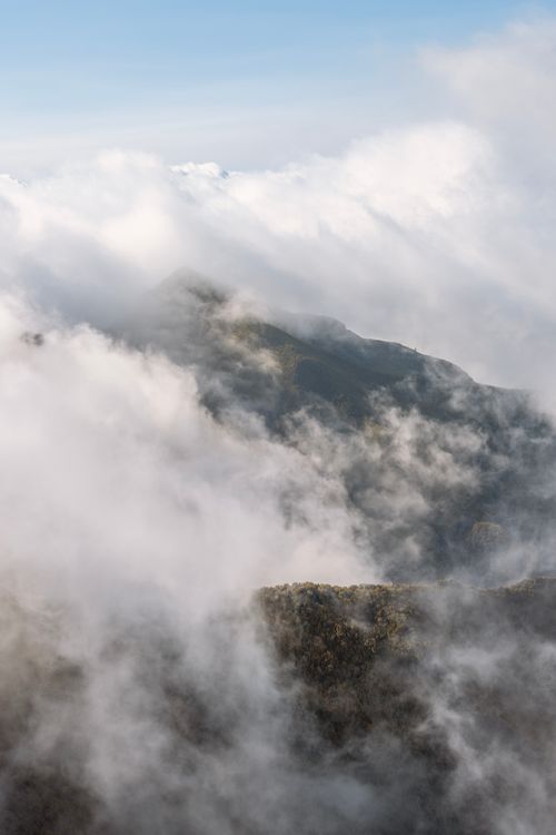 Free Aerial view of rugged mountains blanketed by clouds in Madeira, Portugal. Stock Photo