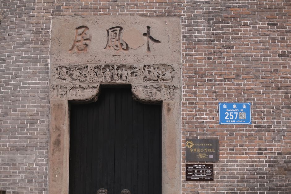 A close-up of a brick wall with intricate Chinese carvings and an address plaque in Baixiang Jie.