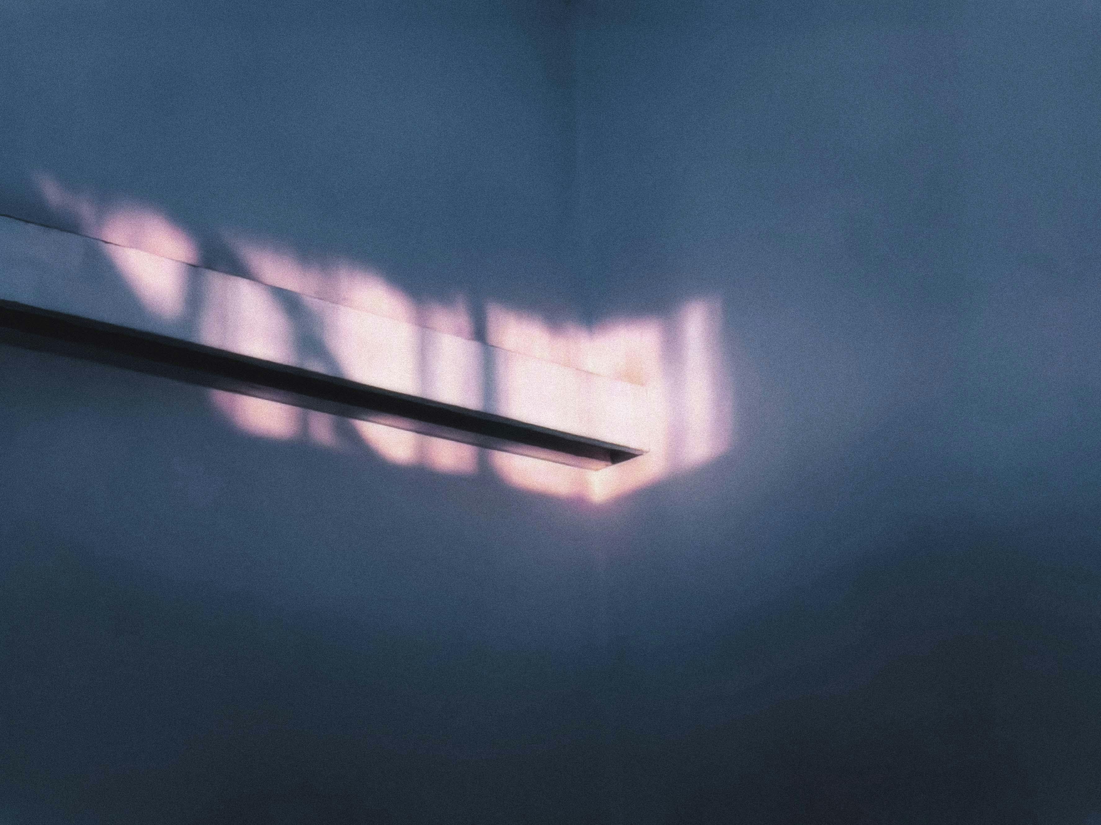 Kostenlos Das Spiel von Licht und Schatten auf einer blauen Wand erzeugt ein abstraktes Muster. Stock-Foto