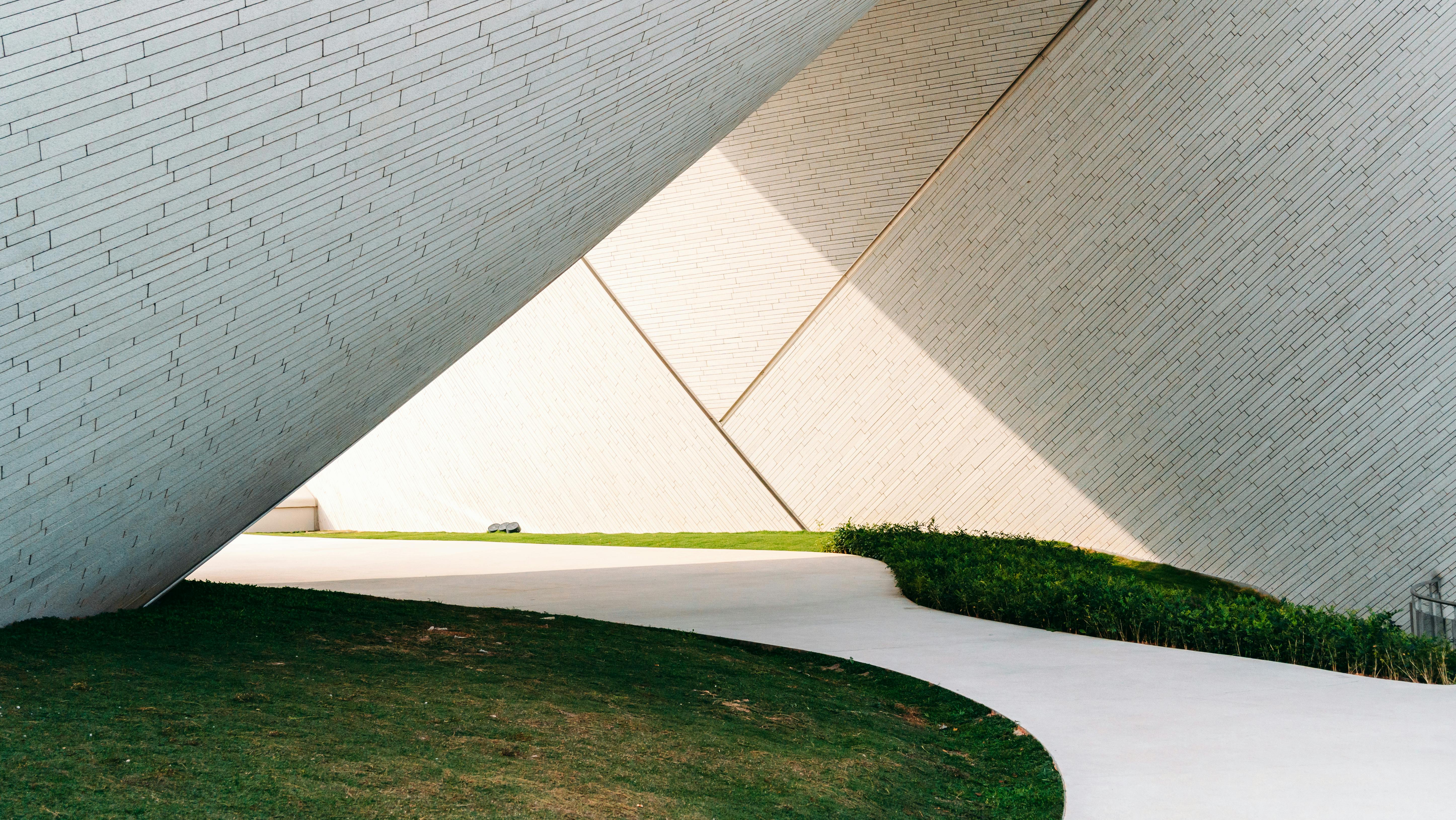 Gratuit Vedere abstractă a arhitecturii moderne, cu o alee geometrică și pereți înclinați, creând umbre izbitoare. Fotografie de stoc