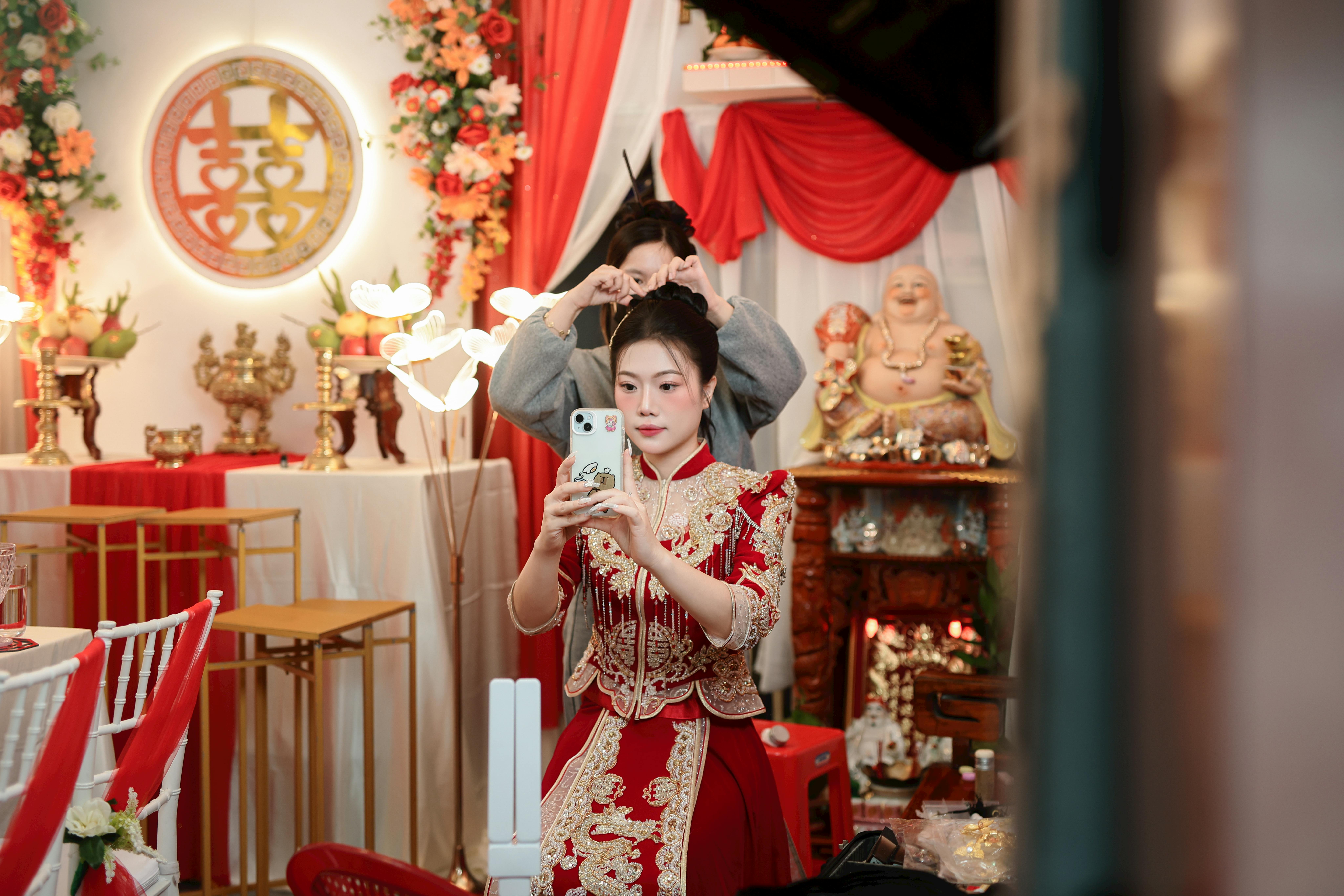 grátis Noiva asiática elegante em traje tradicional, capturando momentos especiais em um ambiente cerimonial. Foto profissional