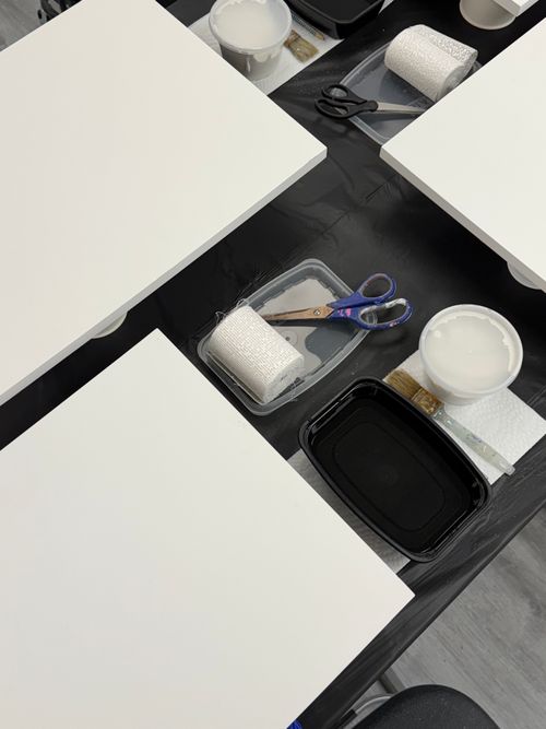 Free Flat lay of an art workshop setup with blank canvases, rollers, scissors, and paint trays. Stock Photo