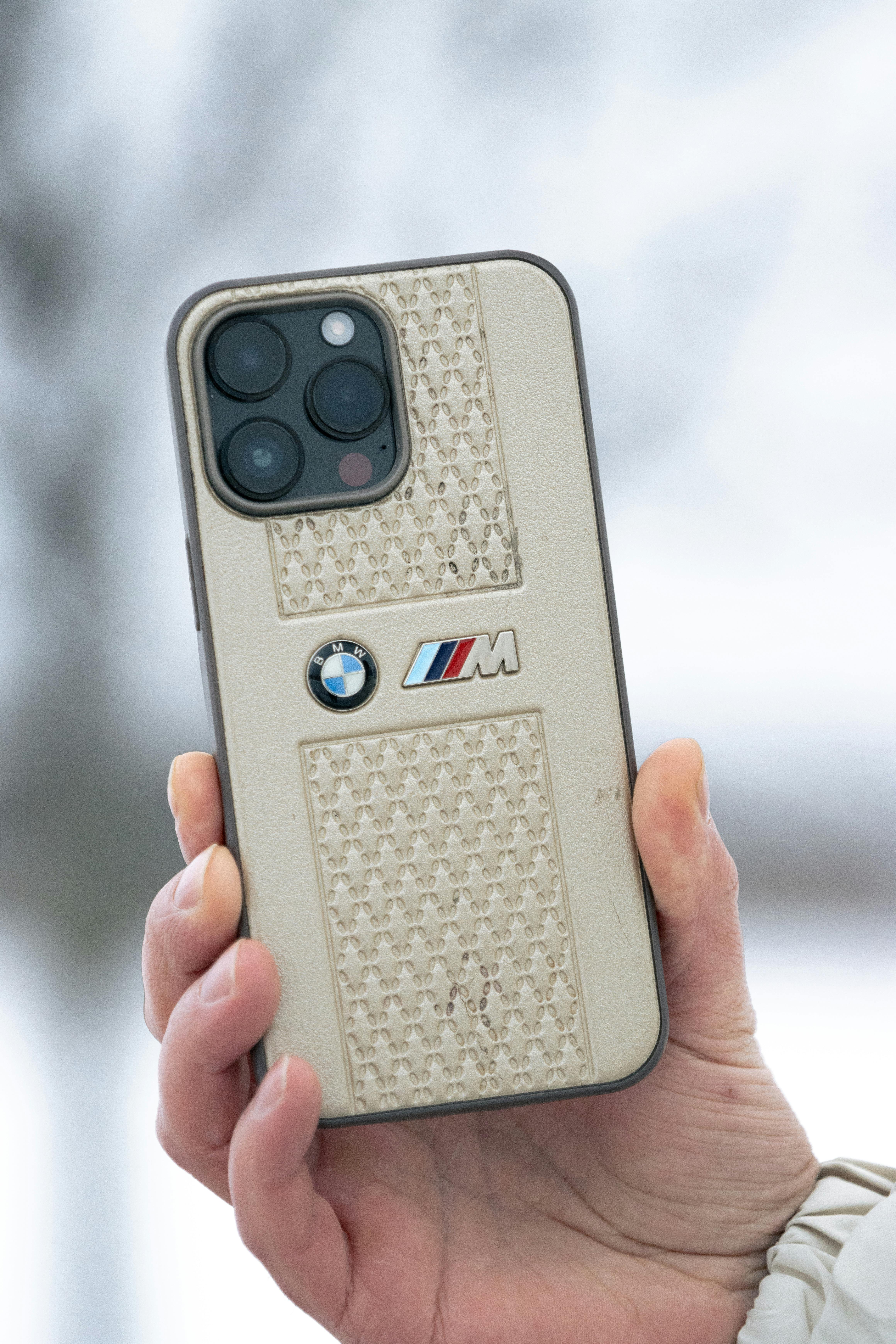 ingyenes Stílusos, BMW logóval ellátott telefontokot tartó kéz télen a szabadban. Stockfotó