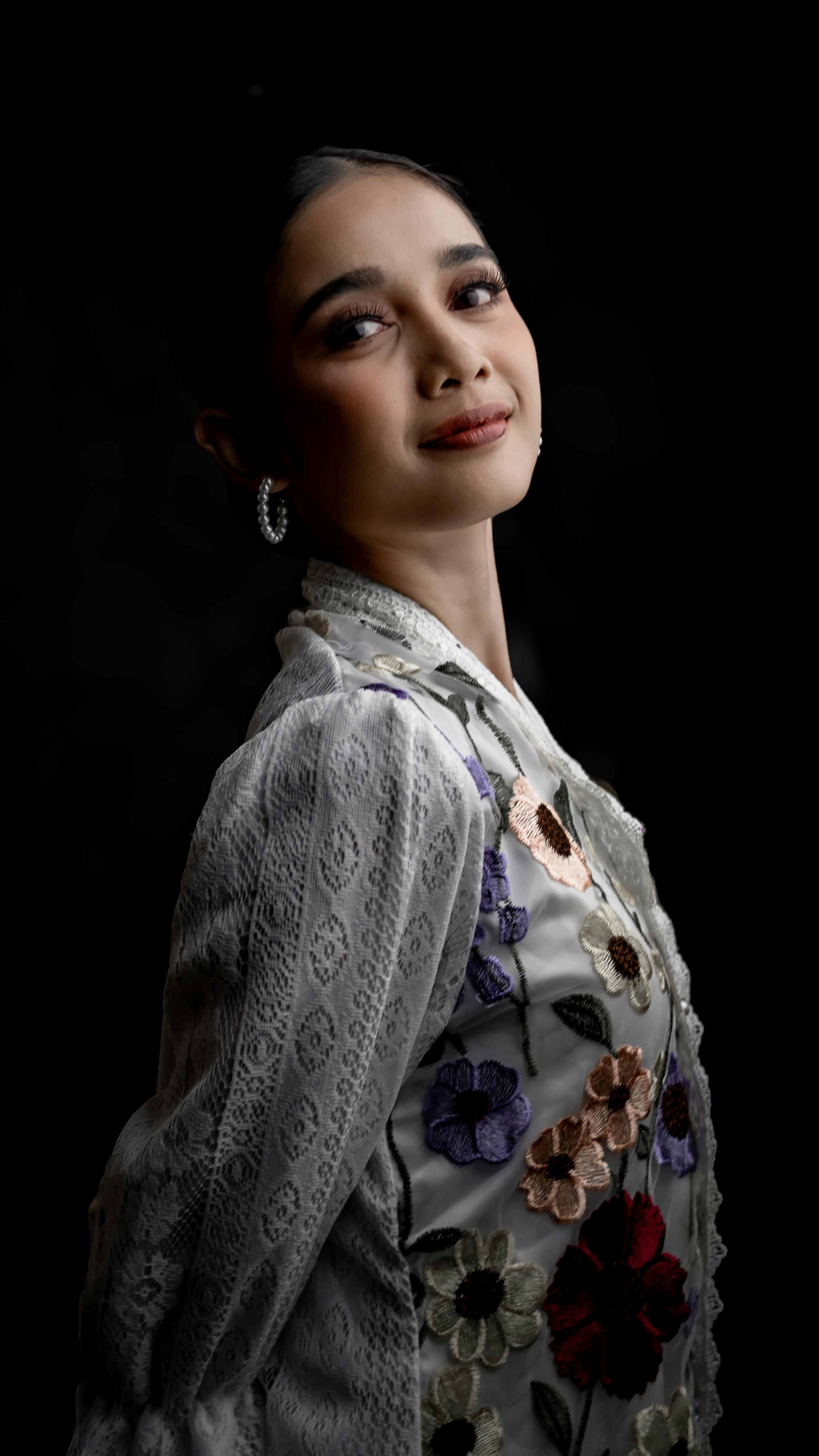 Graceful portrait of a woman in floral attire set against a dark background.
