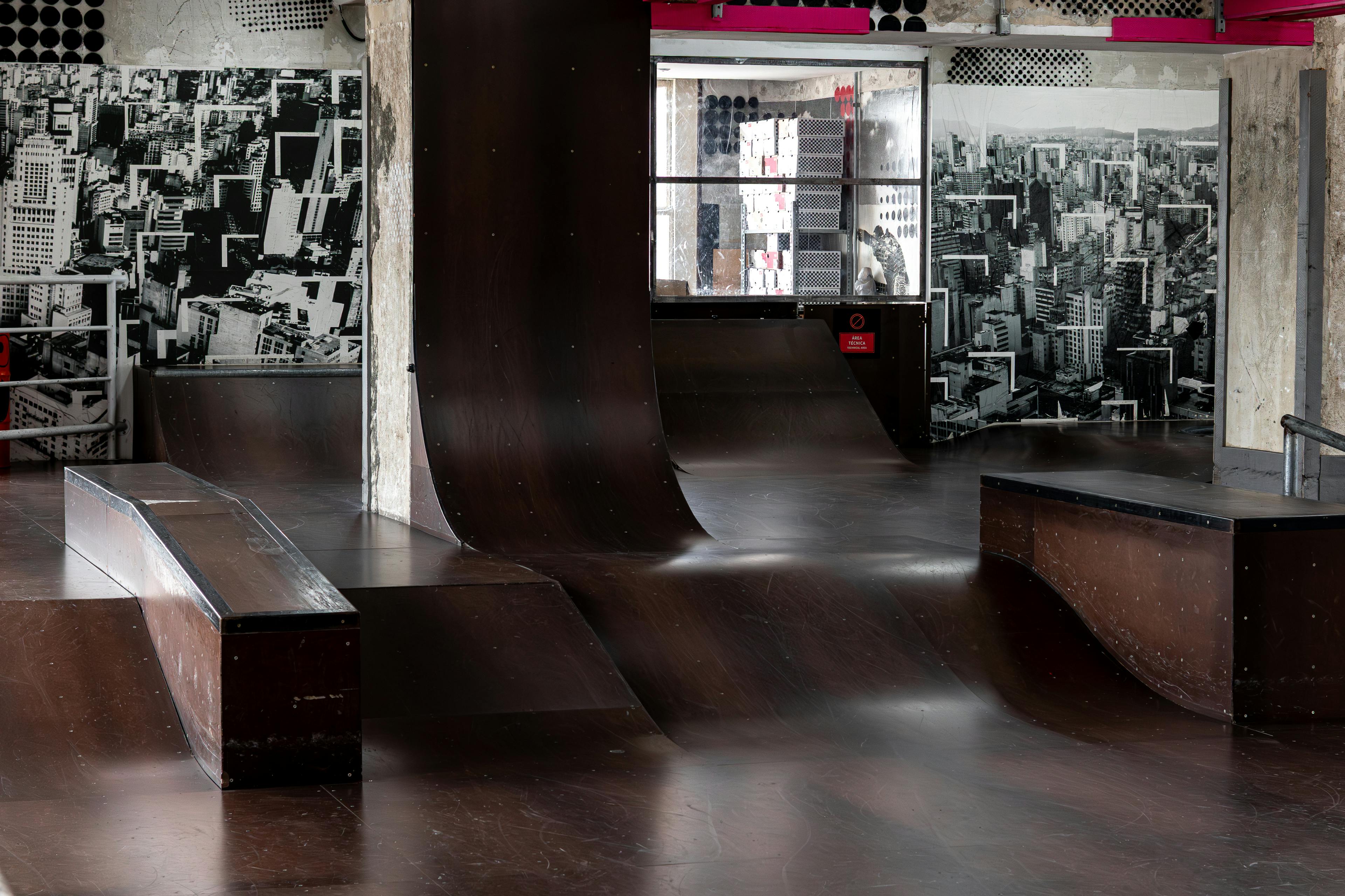 Bezpłatne Nowoczesny kryty skatepark z rampami i muralami przedstawiającymi panoramę miasta, tworzący niepowtarzalny, miejski klimat. Zdjęcie z galerii