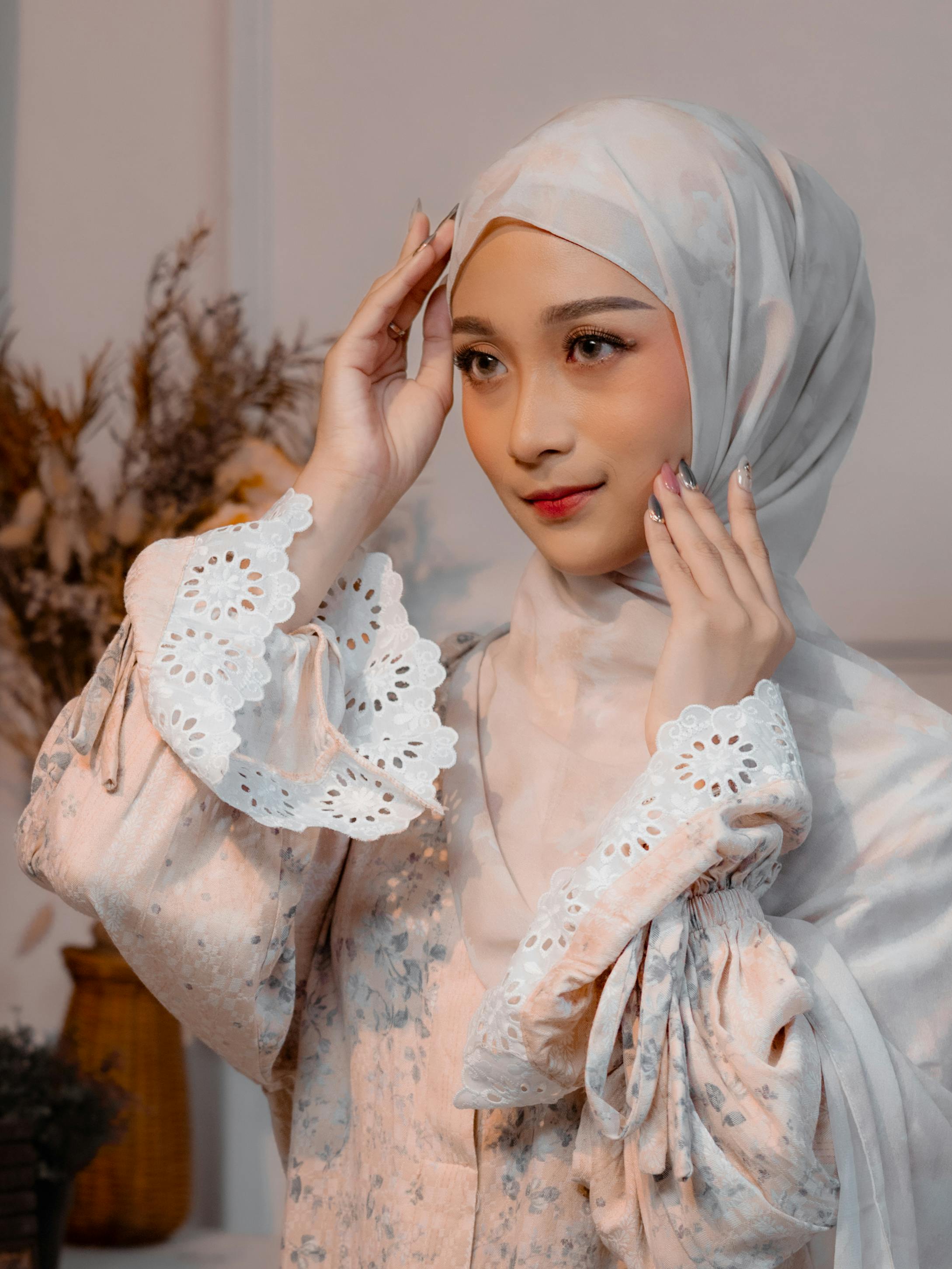 Gratis Una donna che indossa un hijab fantasia con dettagli in pizzo posa in un interno con luci soffuse. Foto a disposizione