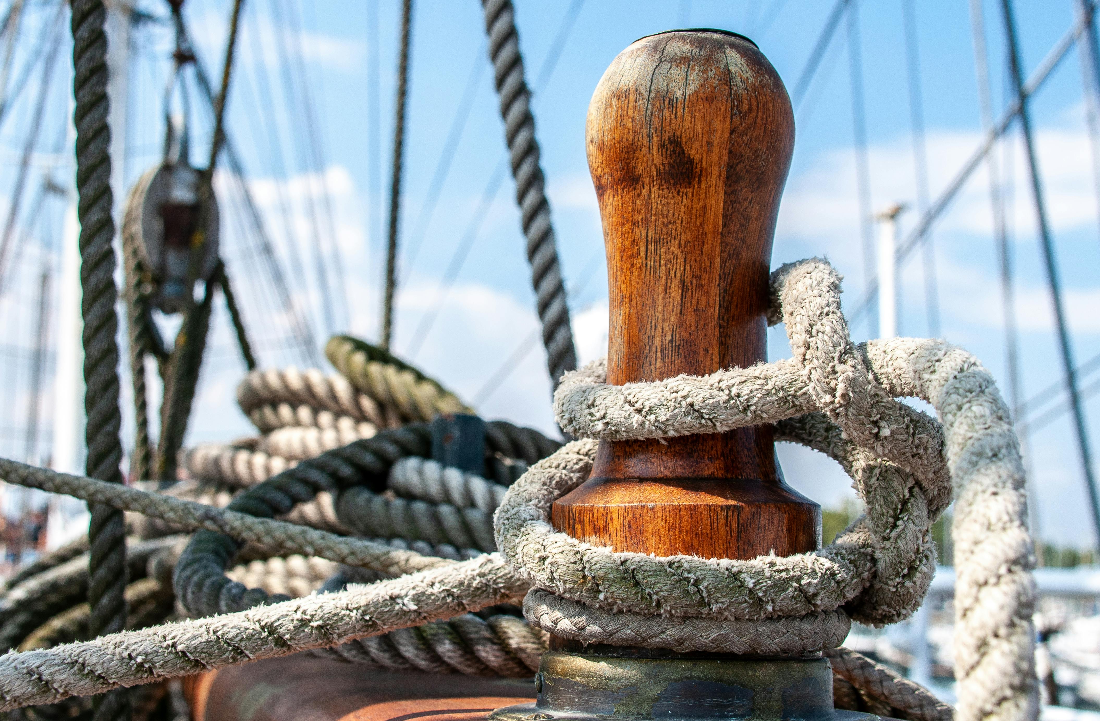 Detailed view of nautical ropes wrapped around a wooden cleat on a ship's deck.