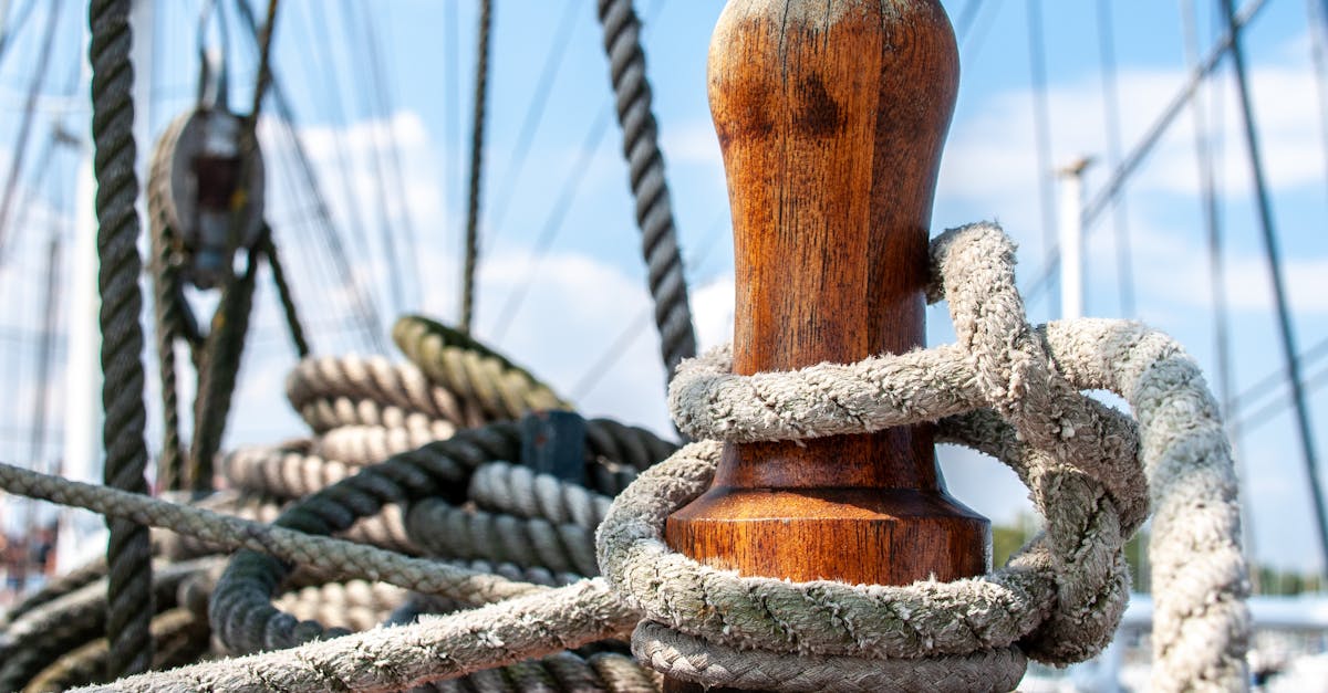 Detailed view of nautical ropes wrapped around a wooden cleat on a ship's deck.