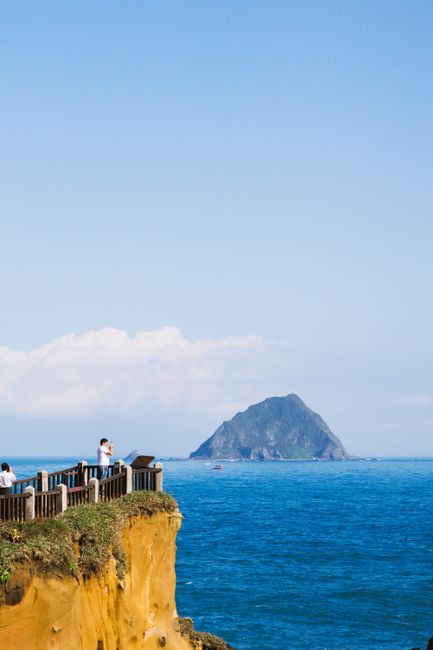 Tourists enjoy a clear view from a clifftop overlooking the ocean towards Lonely Island.