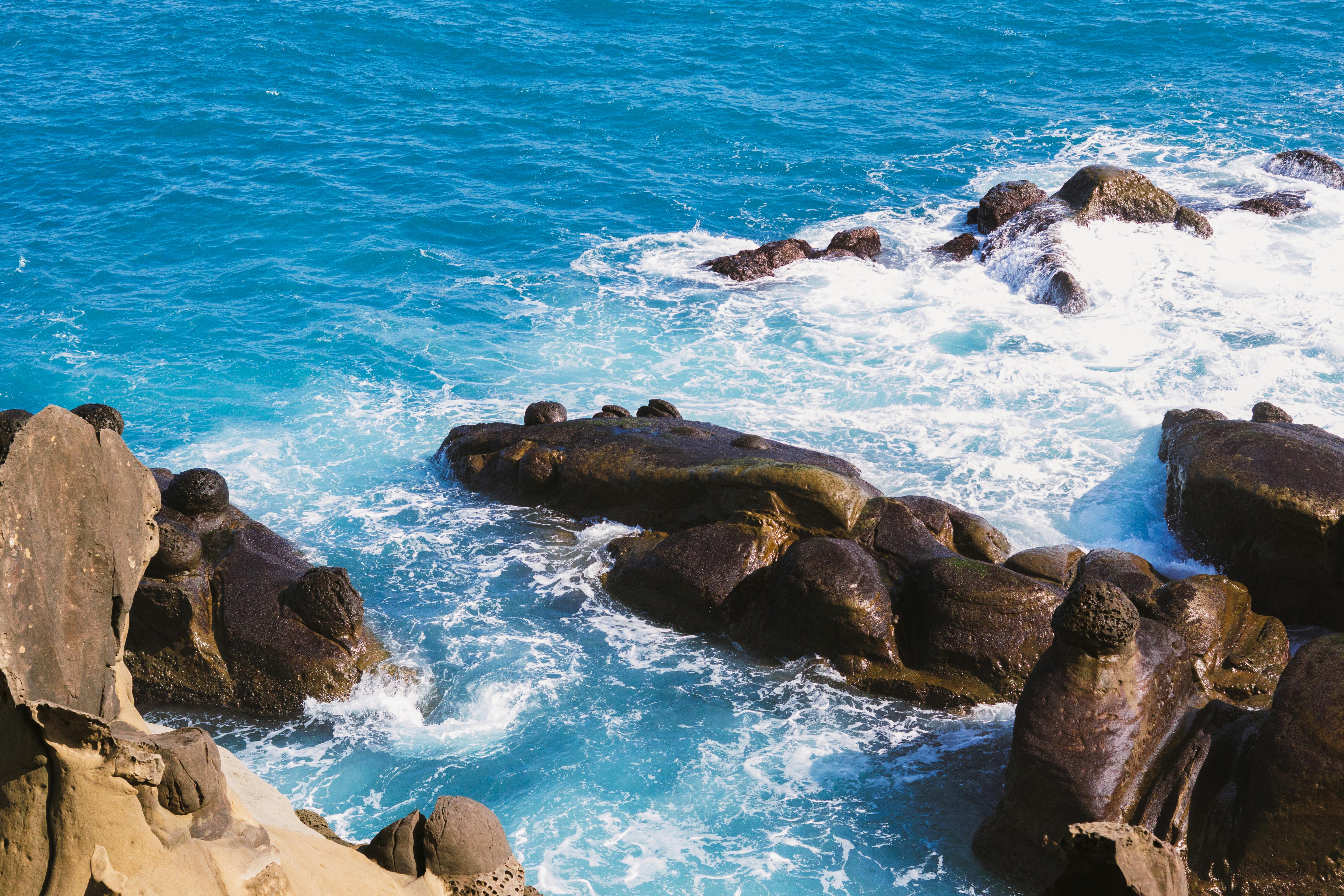 Δωρεάν Εκπληκτική θέα σε απόκρημνους παράκτιους βράχους με τιρκουάζ κύματα του ωκεανού να σκάνε στο φως της ημέρας. Φωτογραφία από στοκ φωτογραφιών