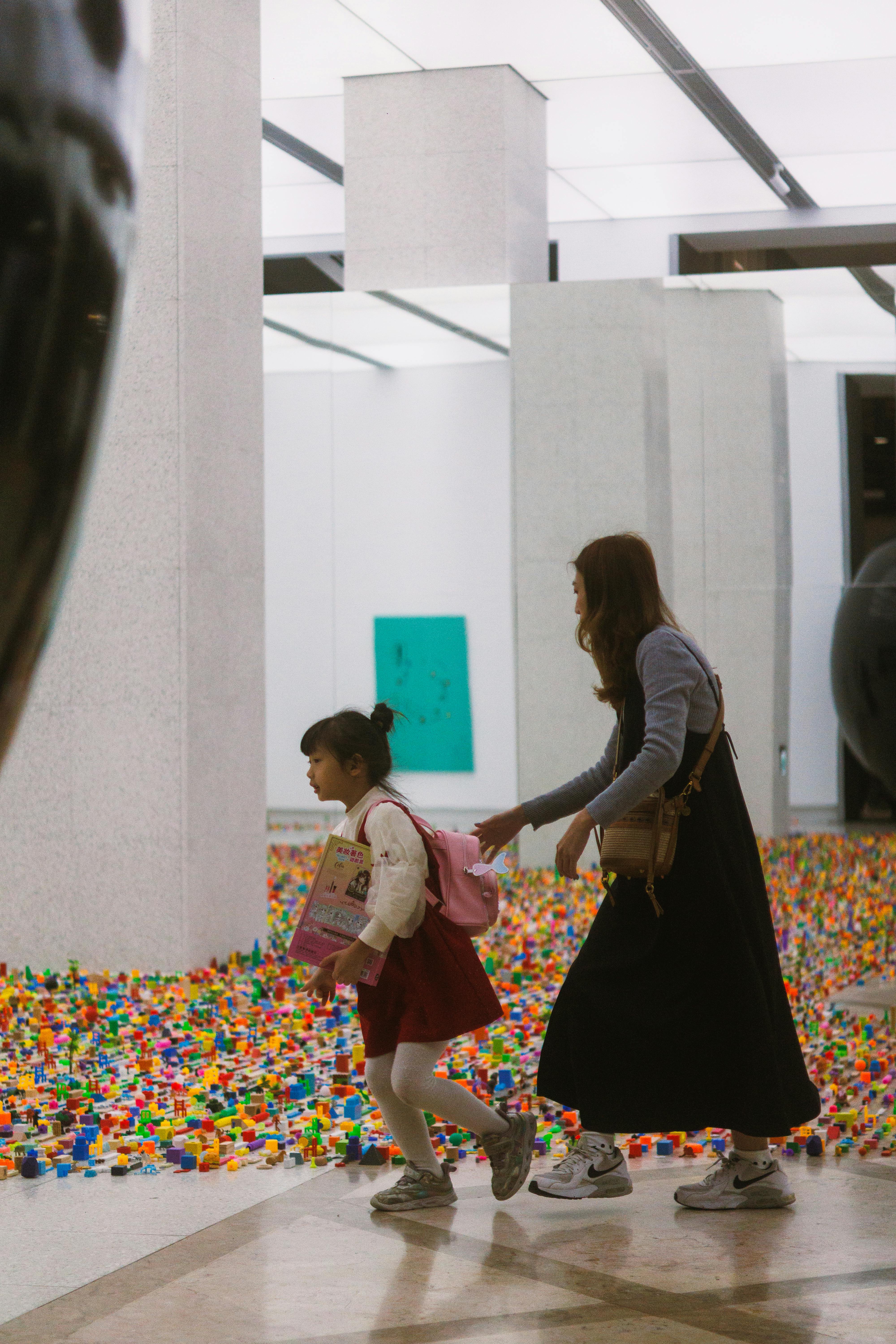 Kostenlos Eine Mutter und ihre Tochter genießen eine Kunstinstallation aus bunten Legosteinen in einer modernen Galerie. Stock-Foto