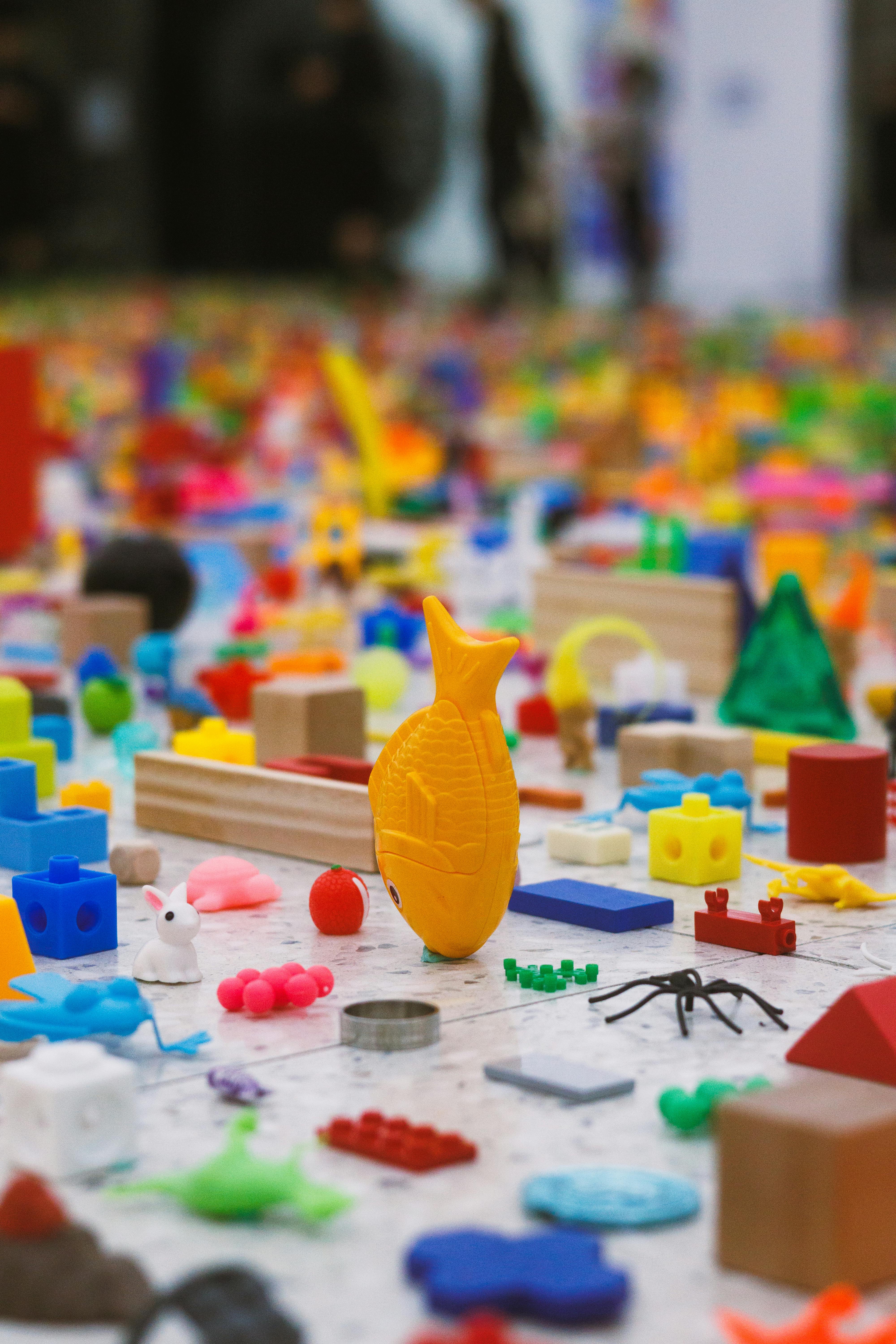 Miễn phí Một loạt các đồ chơi và hình nhân nhỏ đầy màu sắc nằm rải rác trên sàn phòng chơi, tạo nên một khung cảnh vui tươi và sống động. Ảnh lưu trữ