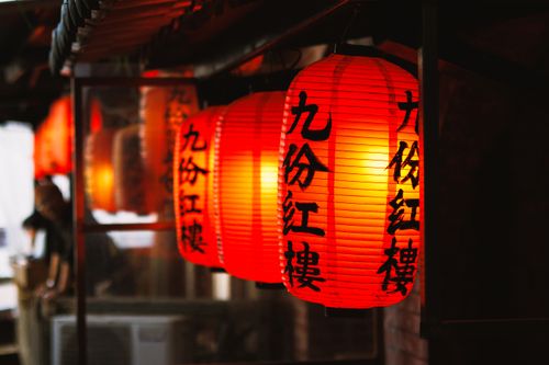 Free Vibrant red lanterns glow warmly, creating an inviting atmosphere in an Asian street market. Stock Photo