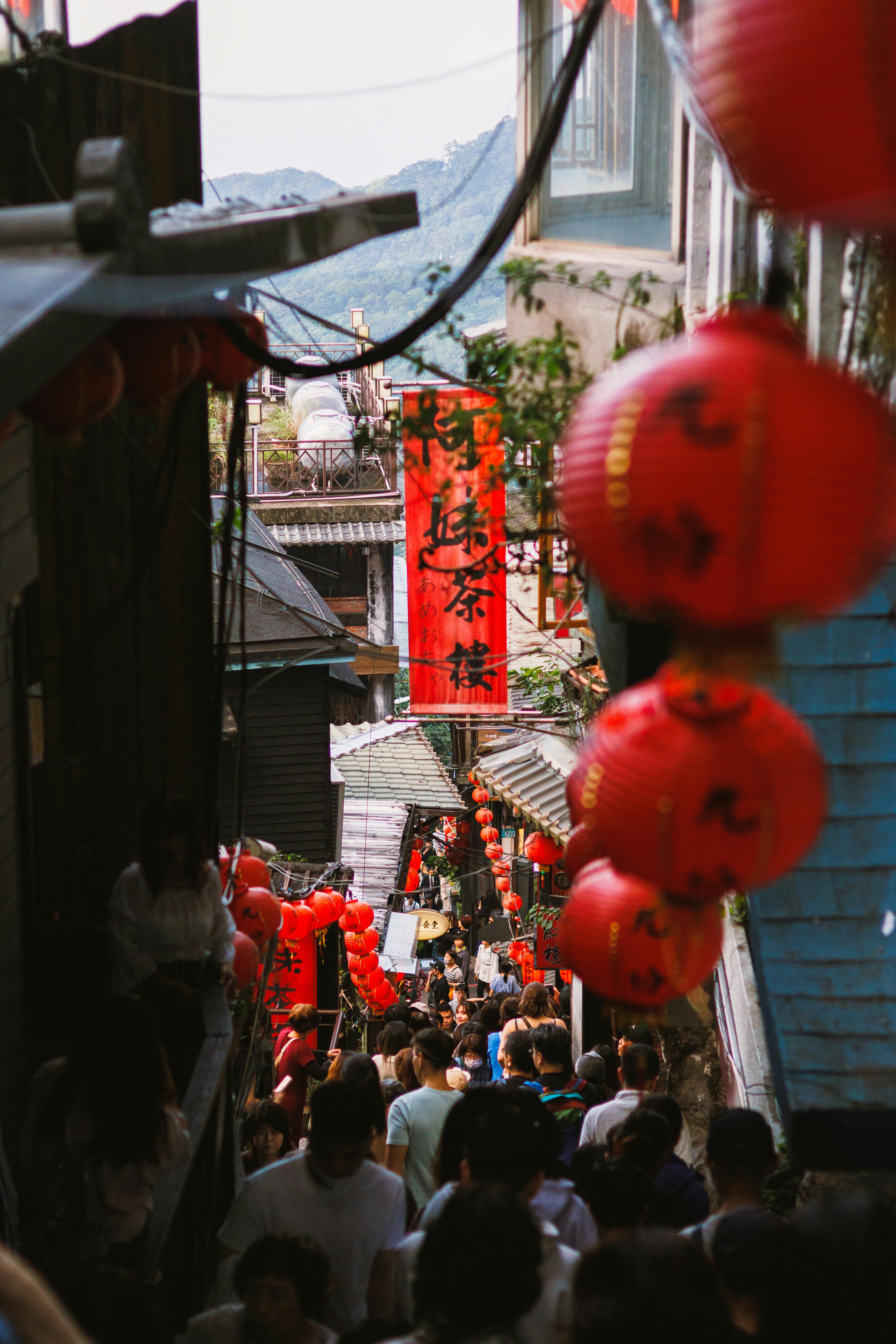 A crowded narrow street with red lanterns and vibrant cultural ambiance.