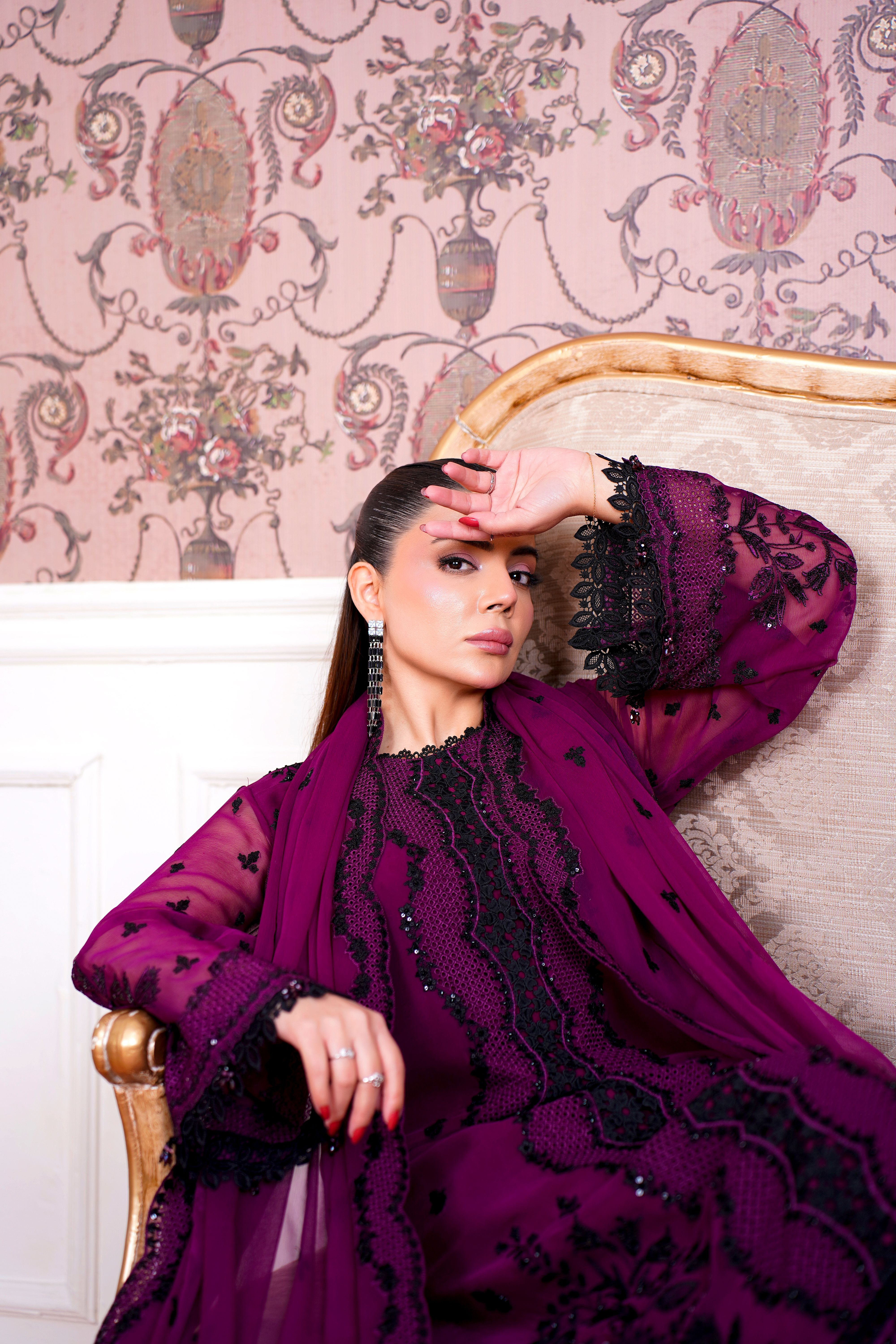 Fashion portrait of a woman in an ornate setting wearing a stunning purple traditional dress.