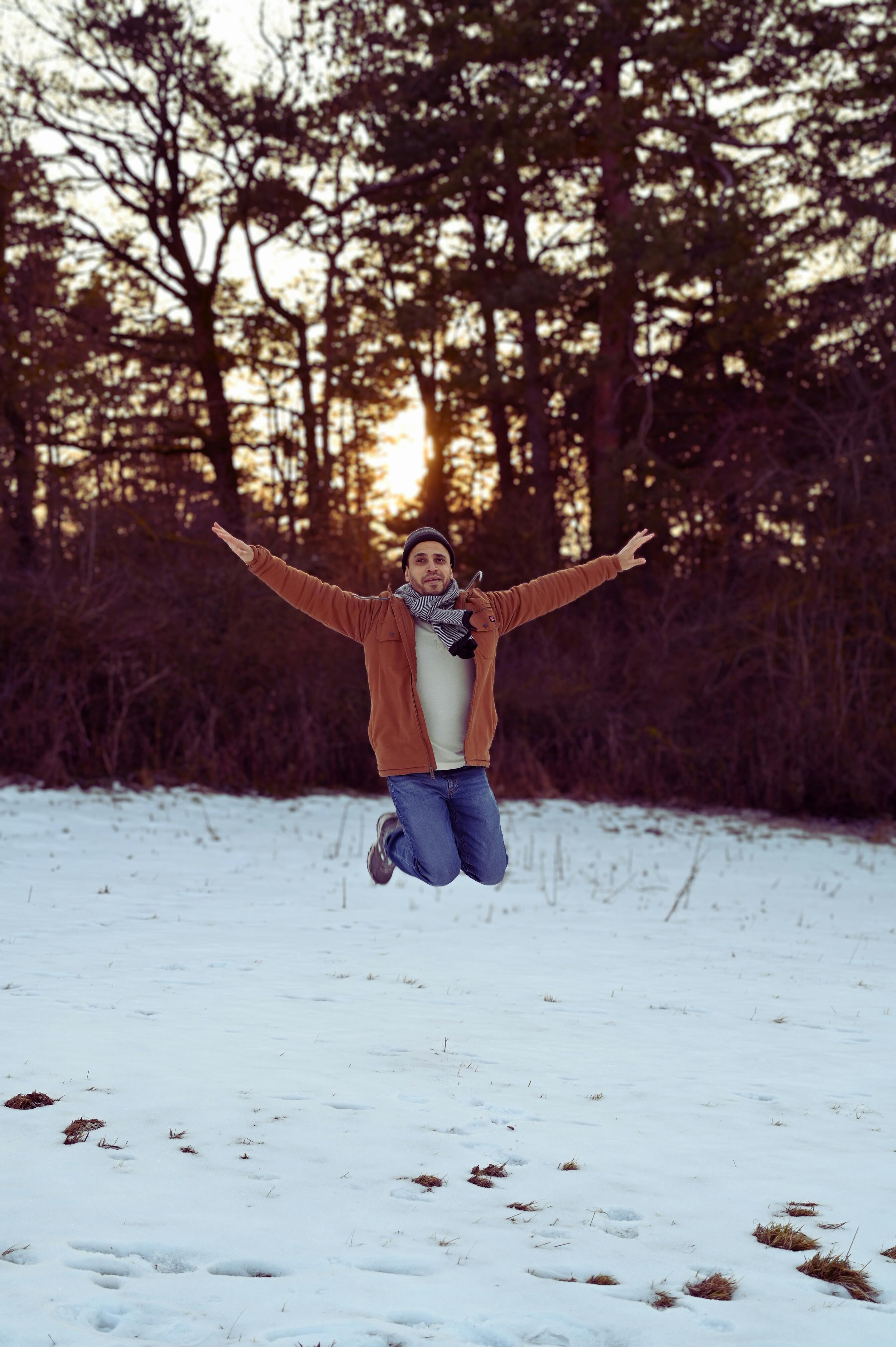 Kostenlos Mann springt bei Sonnenuntergang in einem verschneiten Wald, Deutschland, Winterszene. Stock-Foto