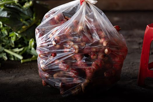 Bag of fresh galangal roots at a market stall in Nam Dinh, Vietnam, showcasing local produce.