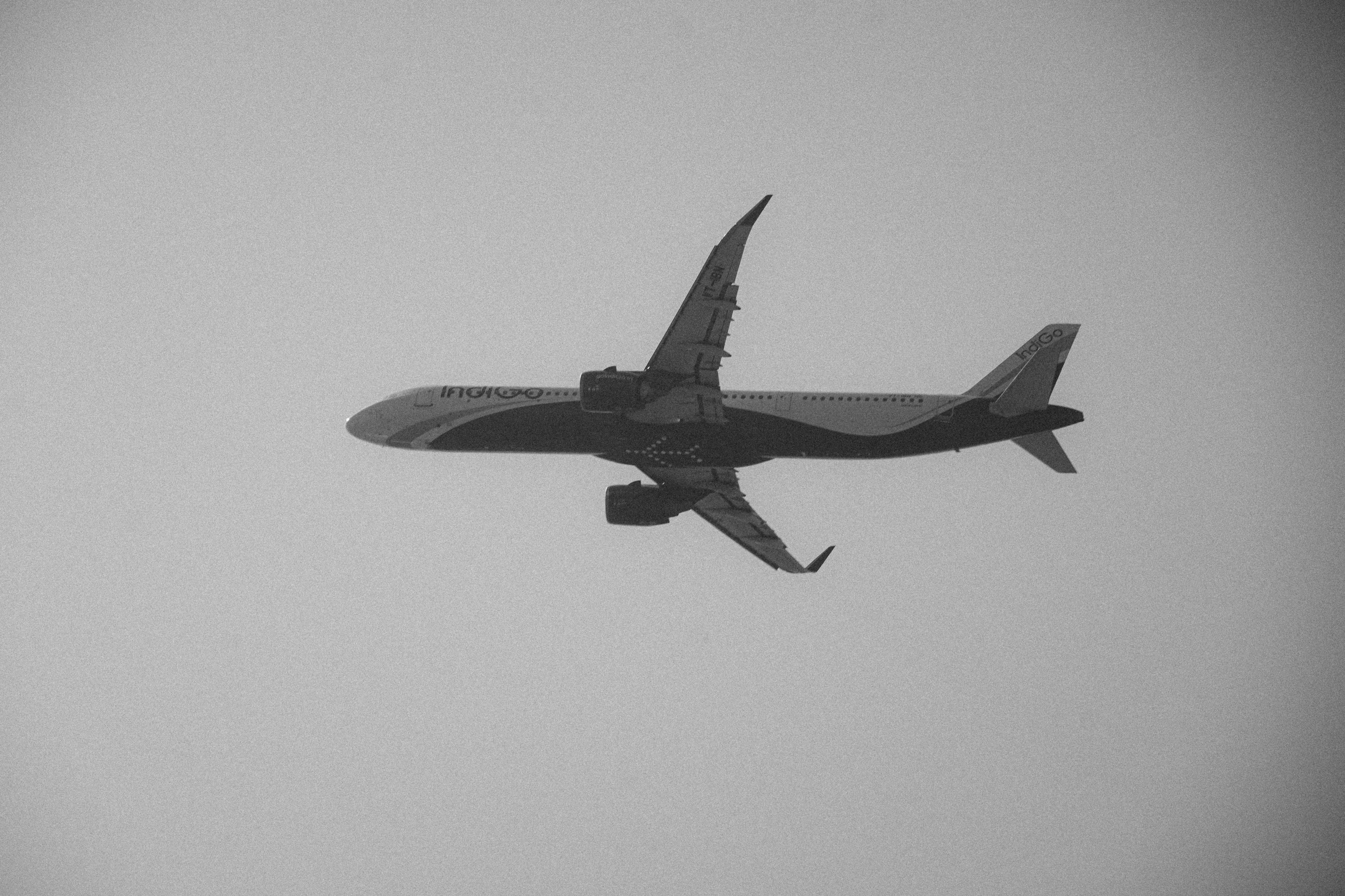 Gratis Et monokrom bilde av et kommersielt fly som flyr høyt på klar himmel. Arkivbilde