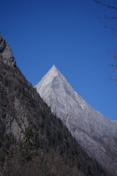 A stunning view of a towering mountain peak with a clear blue sky in the background.