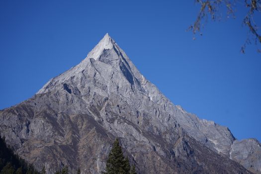 Stunning view of a towering mountain peak under a clear blue sky, ideal for nature and travel themes.
