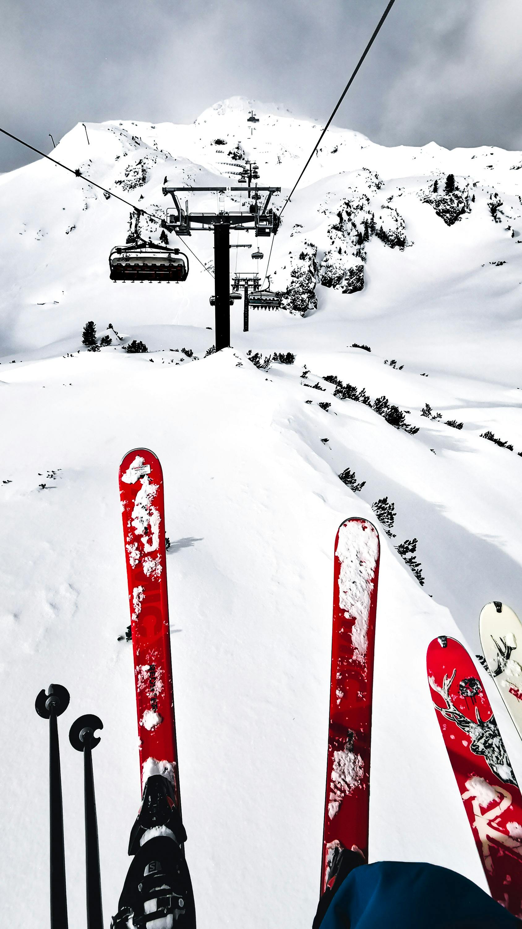 Skis and poles on a snowy slope in Austria with a ski lift and mountain view.