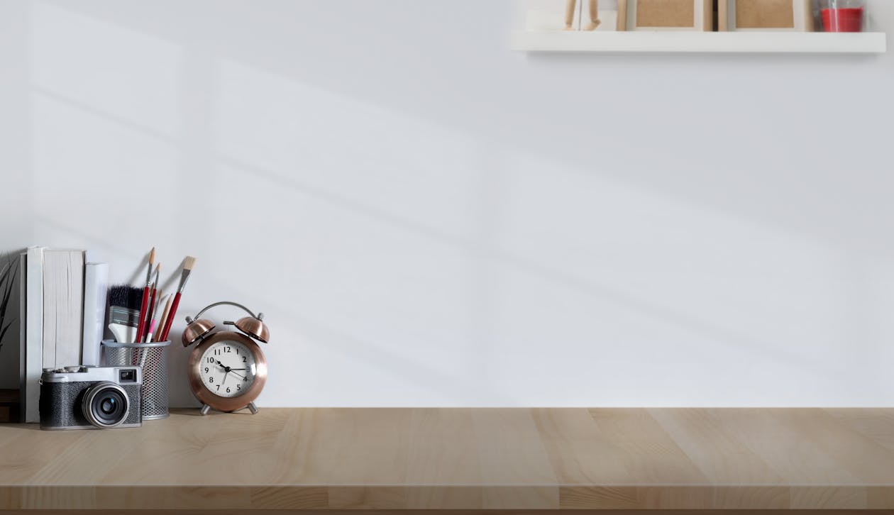 Alarm Clock And Analog Camera On Wooden Desk