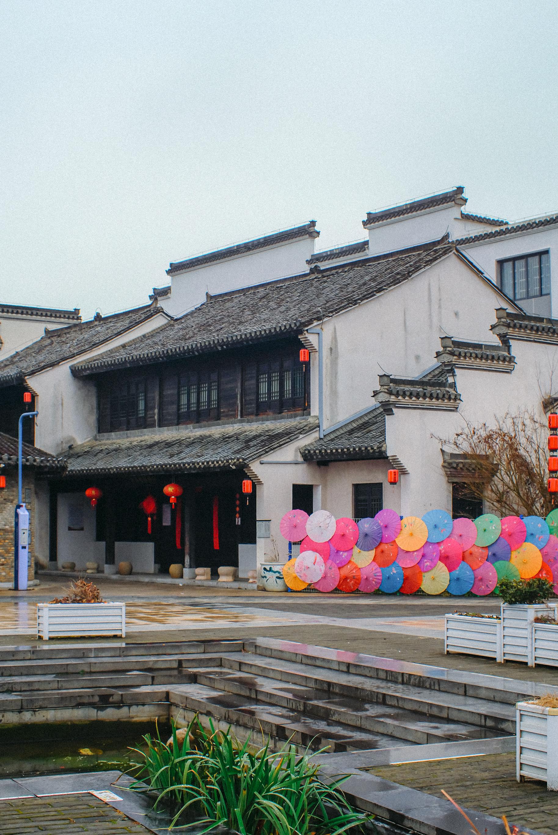 免費 街景：一座中國式建築，裝飾著色彩鮮豔的雨傘和節慶燈籠。 圖庫相片