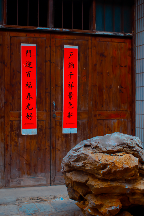 Free Rustic wooden door with Chinese New Year red banners and a large rock. Stock Photo