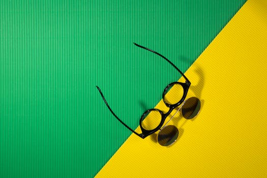 Sunglasses on a vibrant green and yellow background creating a summer vibe.