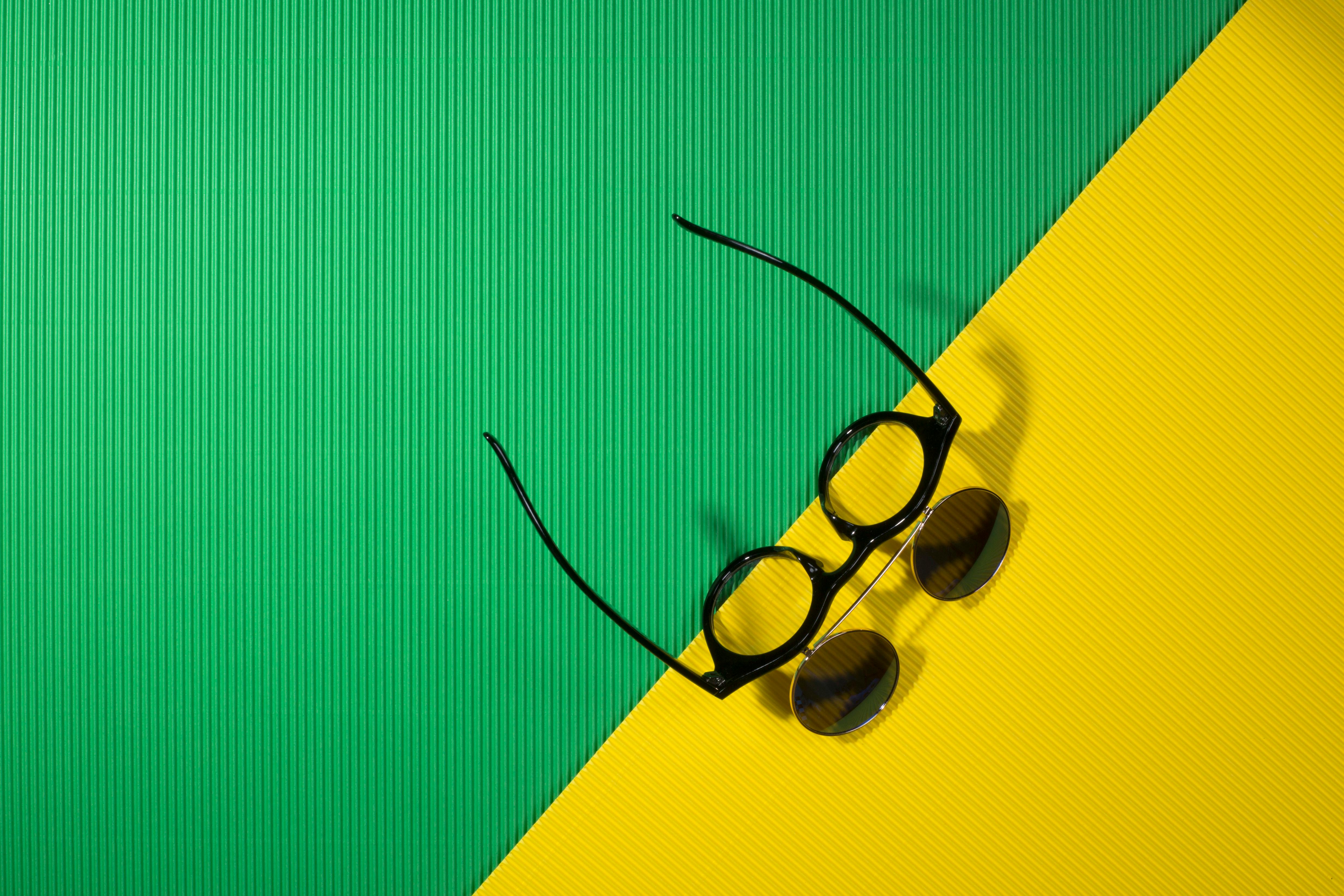 Free Sunglasses on a vibrant green and yellow background creating a summer vibe. Stock Photo