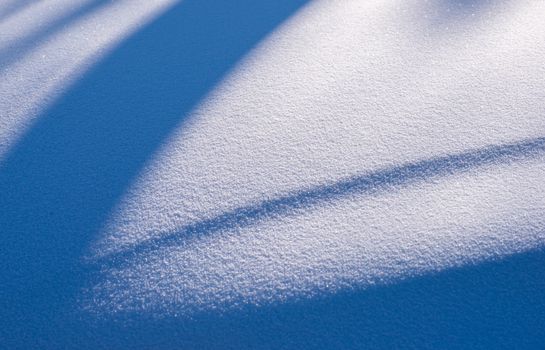 Close-up of snow with soft shadows creating a serene winter scene.