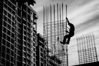 Silhouette of Man Holding onto Metal Frame