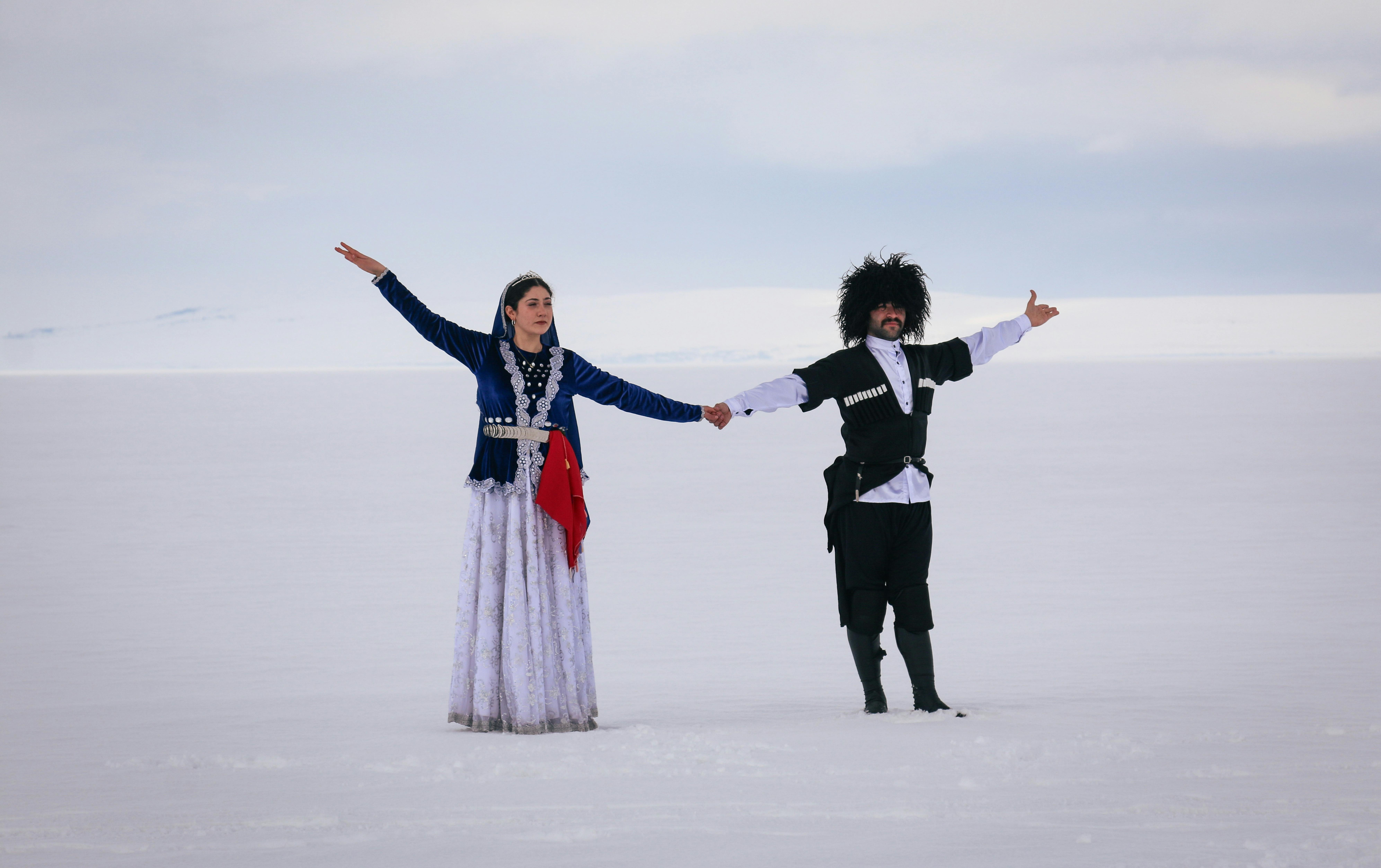 Caucasian dancers in traditional attire on a snowy landscape in Arpaçay, Kars, Türkiye.